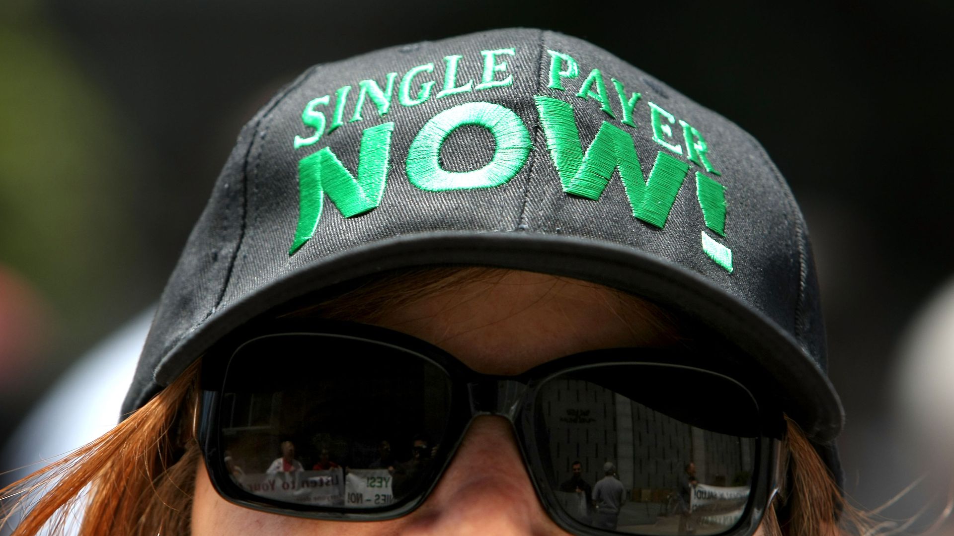 Woman wearing a hat that says, "Single payer now!"