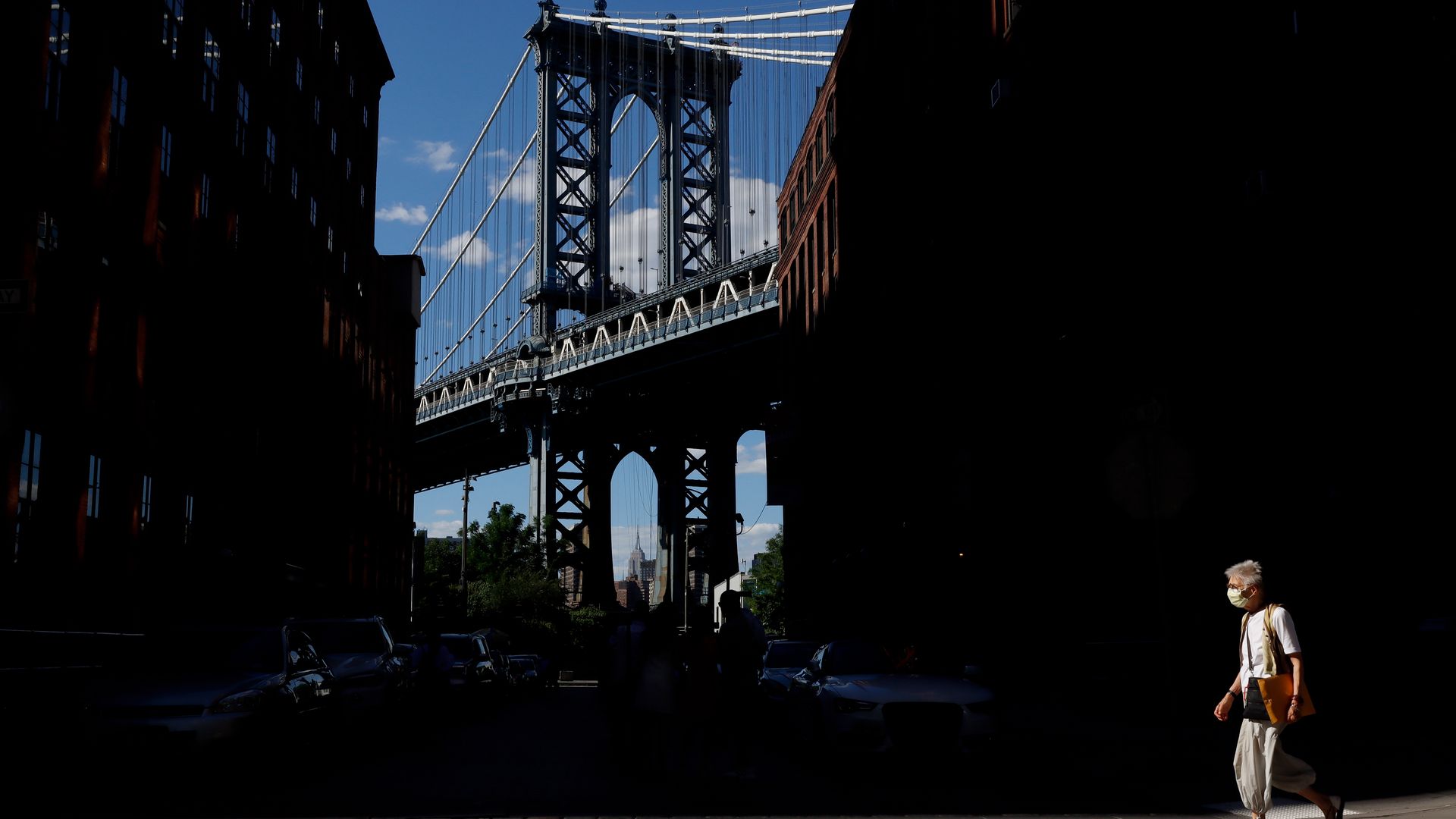 : The Empire State Building is seen through the Manhattan Bridge.