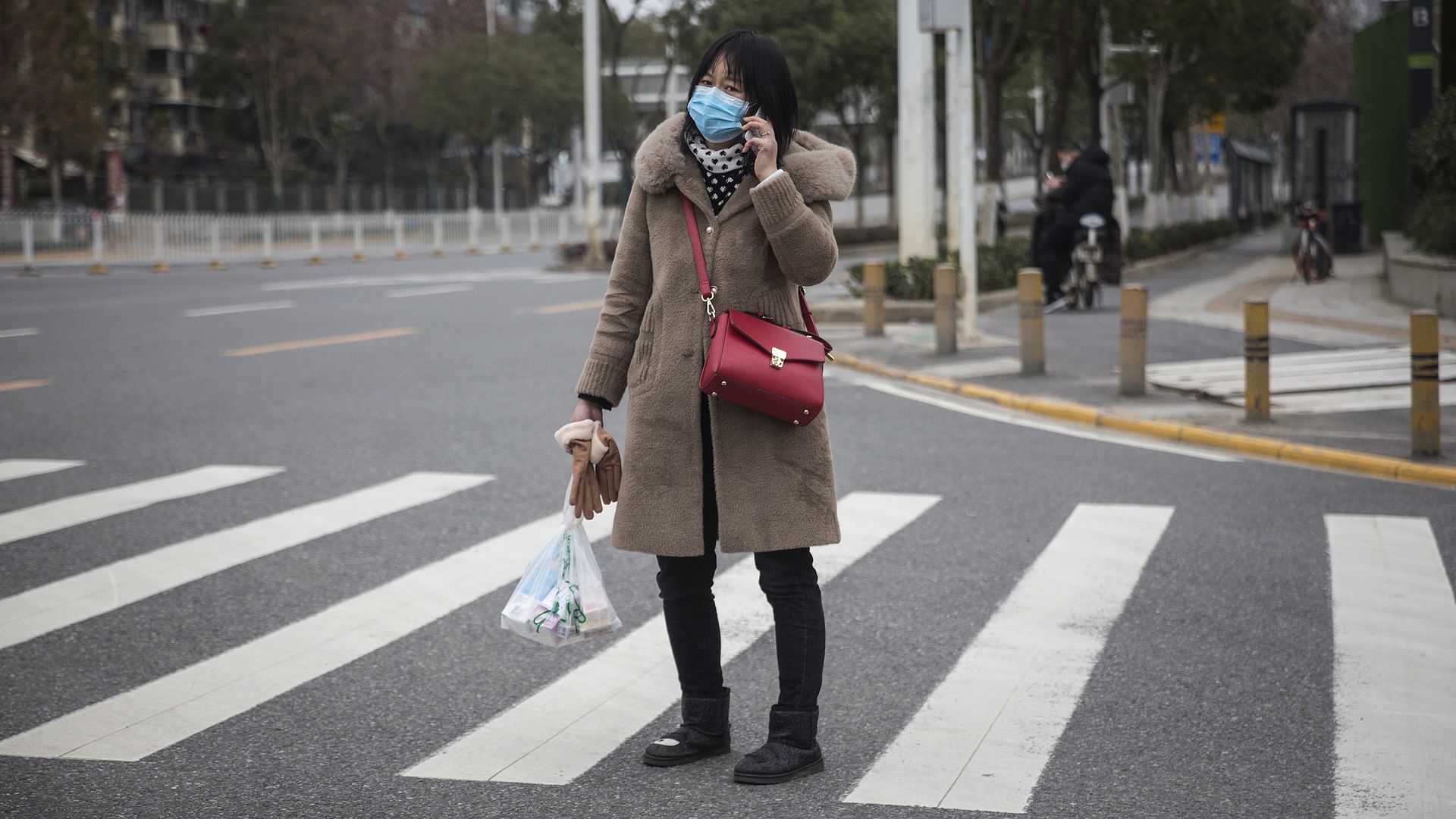 In this image, a woman talks on the phone while standing in a crosswalk in Wuhan, China