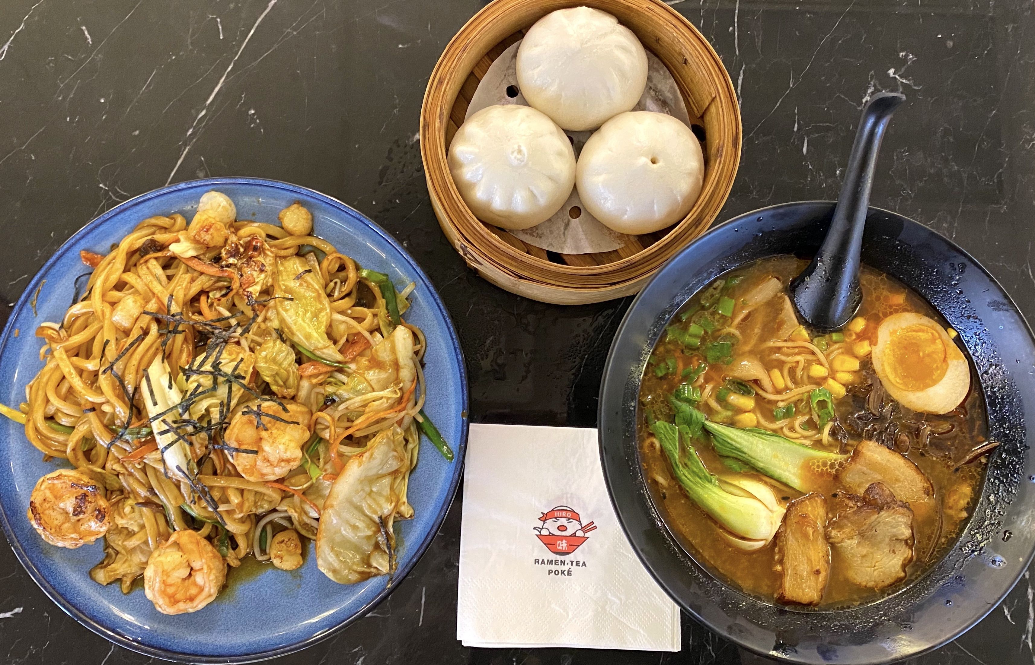 An overview of a seafood noodle stir fry, pork buns and ramen