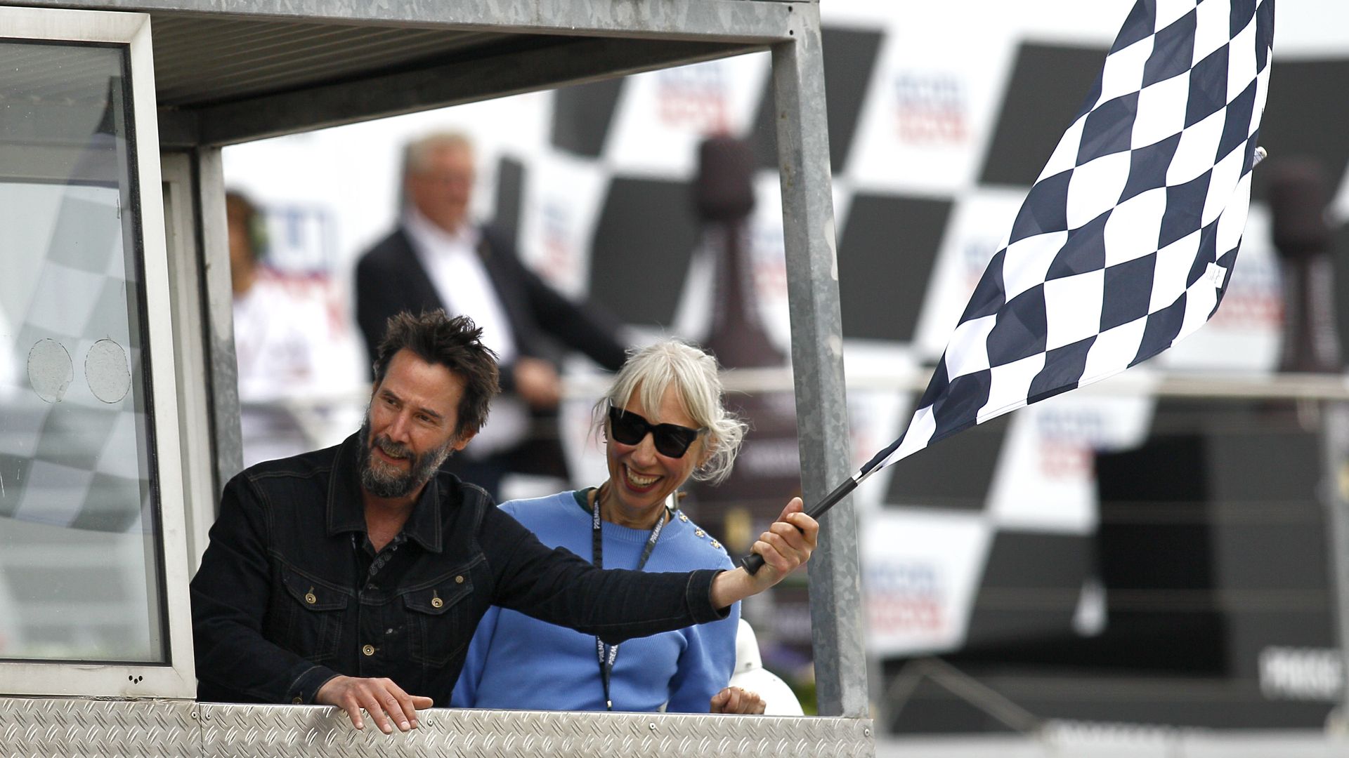  Actor Keanu Reeves and Alexandra Grant wave the checkered flag at the MotoGP of Germany at the Sachsenring Circuit on July 07, 2024 in Hohenstein-Ernstthal, Germany.