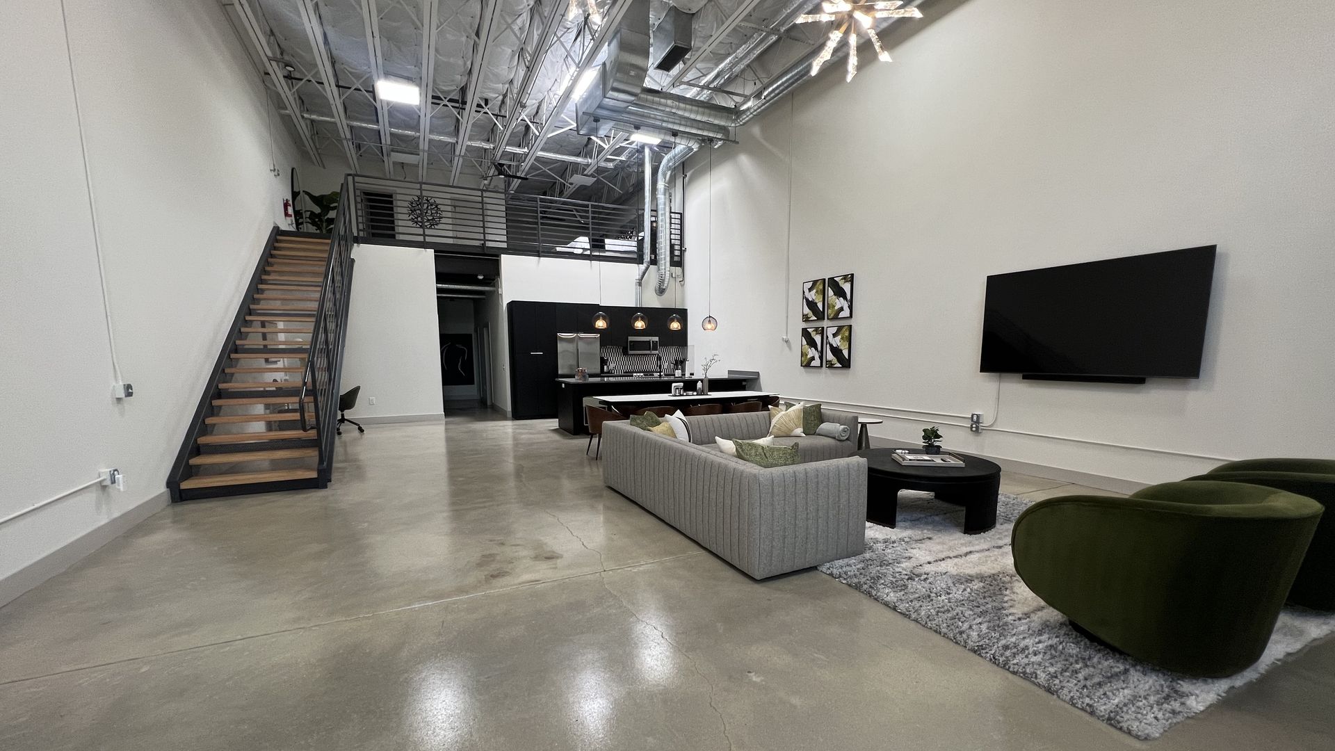 A room in a large, spacious loft with concrete floors. 
