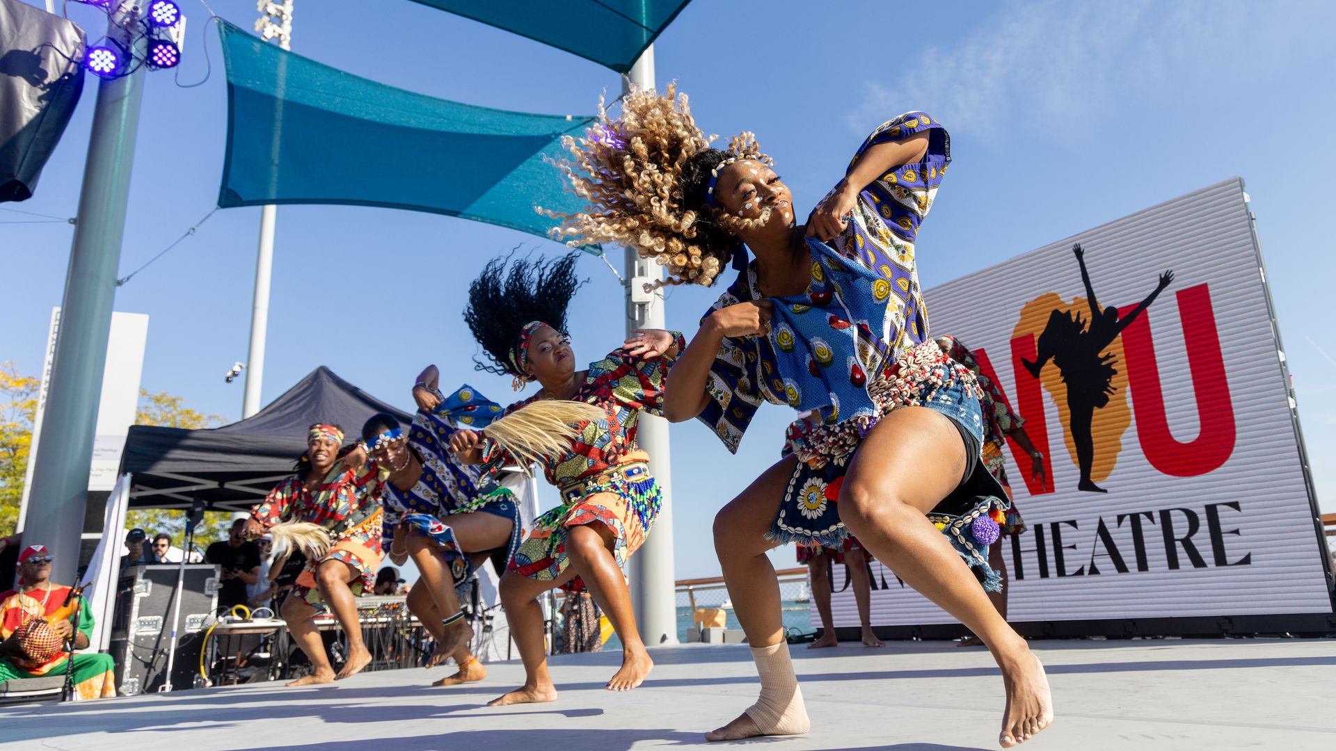 People dancing on a stage by the lake 