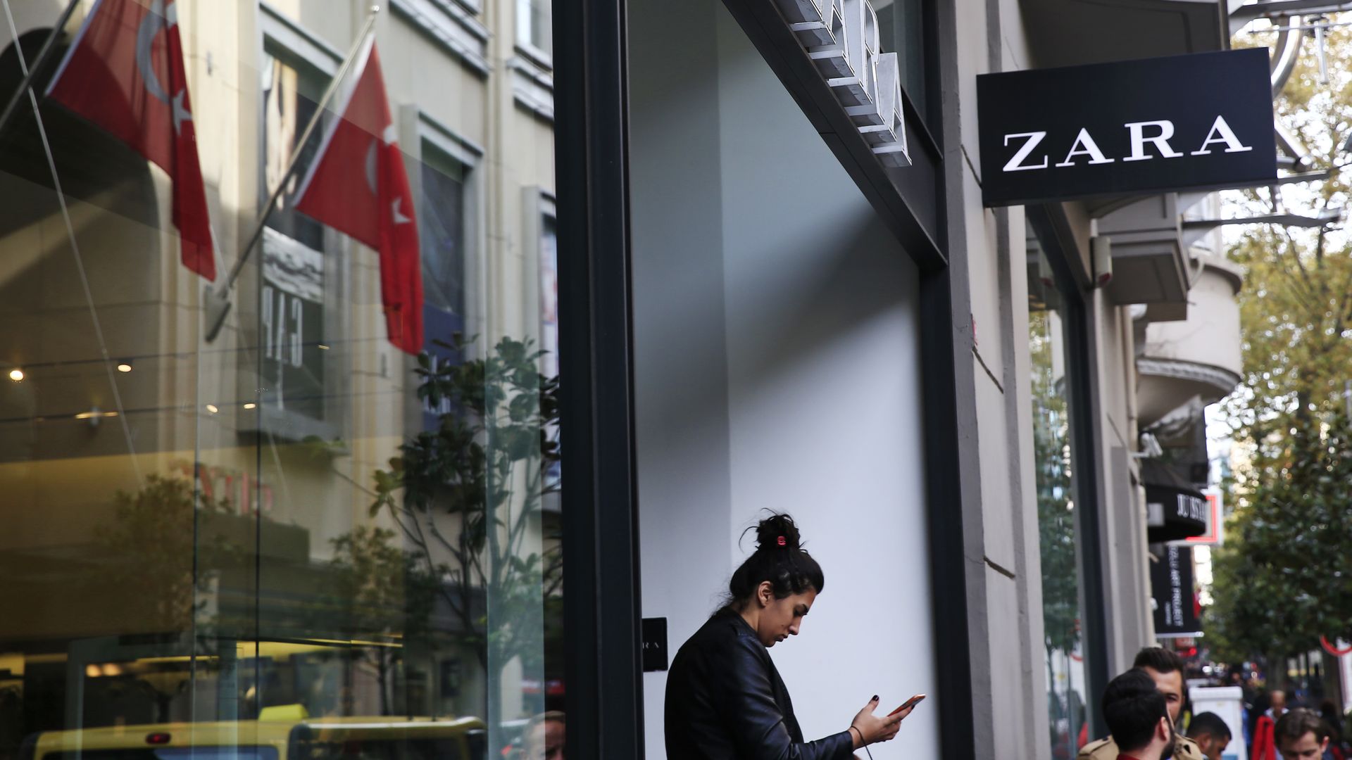 Photo of women gazing at cellphone in front of Zara store in an upscale Istanbul neighborhood