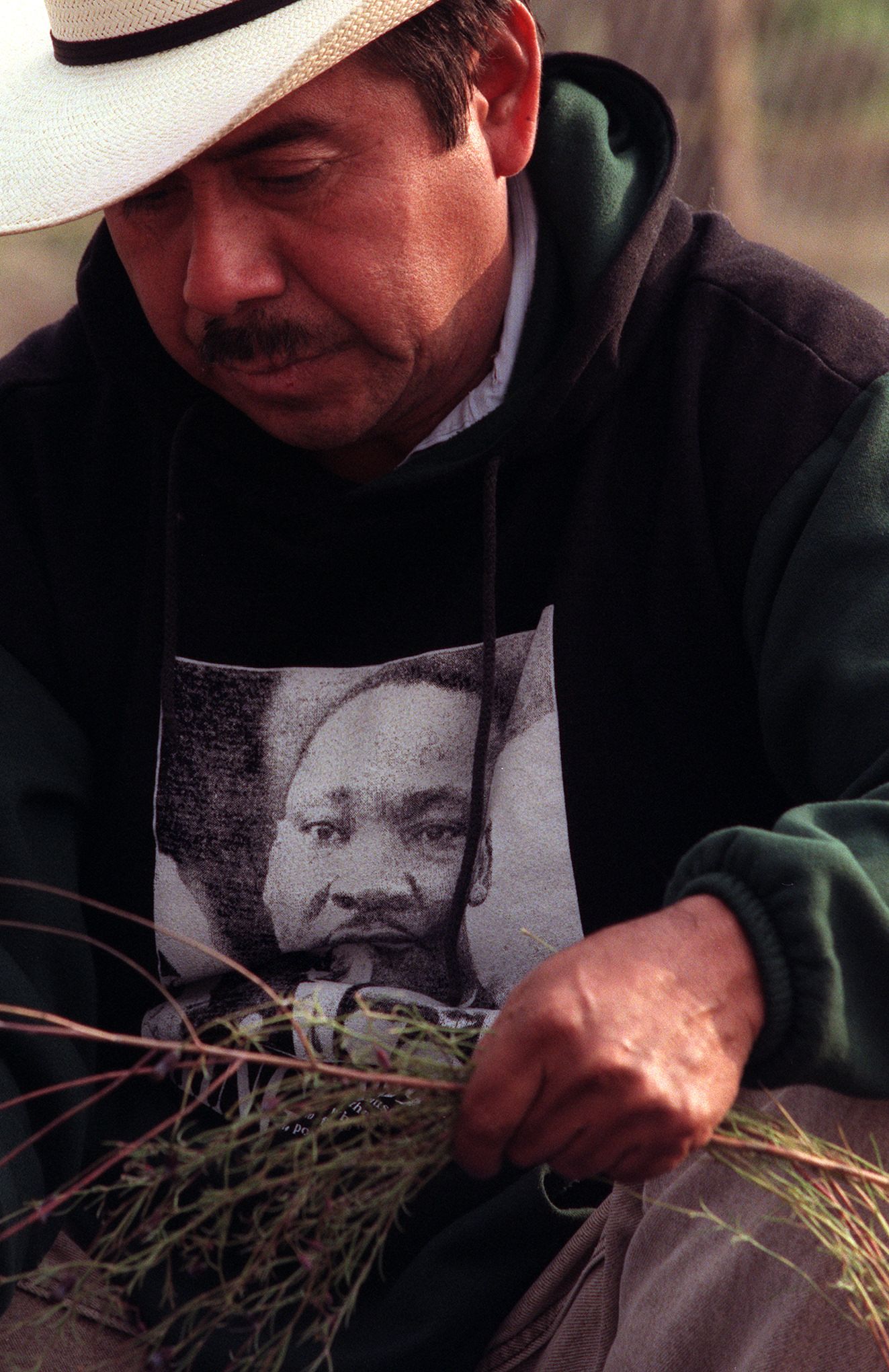 Gaspar Carmen wears a Martin Luther King Jr. sweatshirt as he works in a communal vegetable garden where Latinos and African Americans till their plots side by side in Los Angeles.