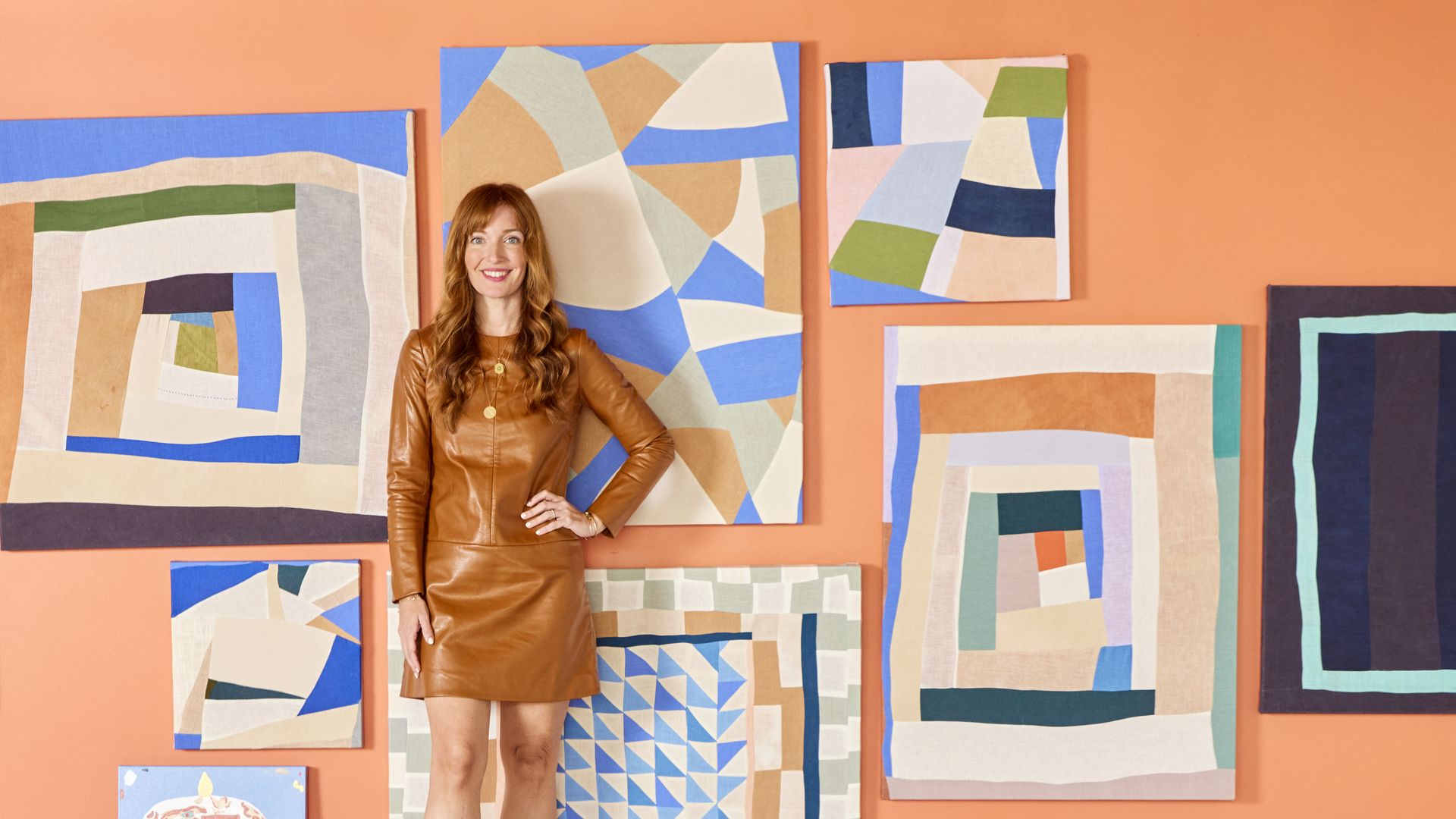 Liz lidgett stands on a counter in front of a bunch of paintings