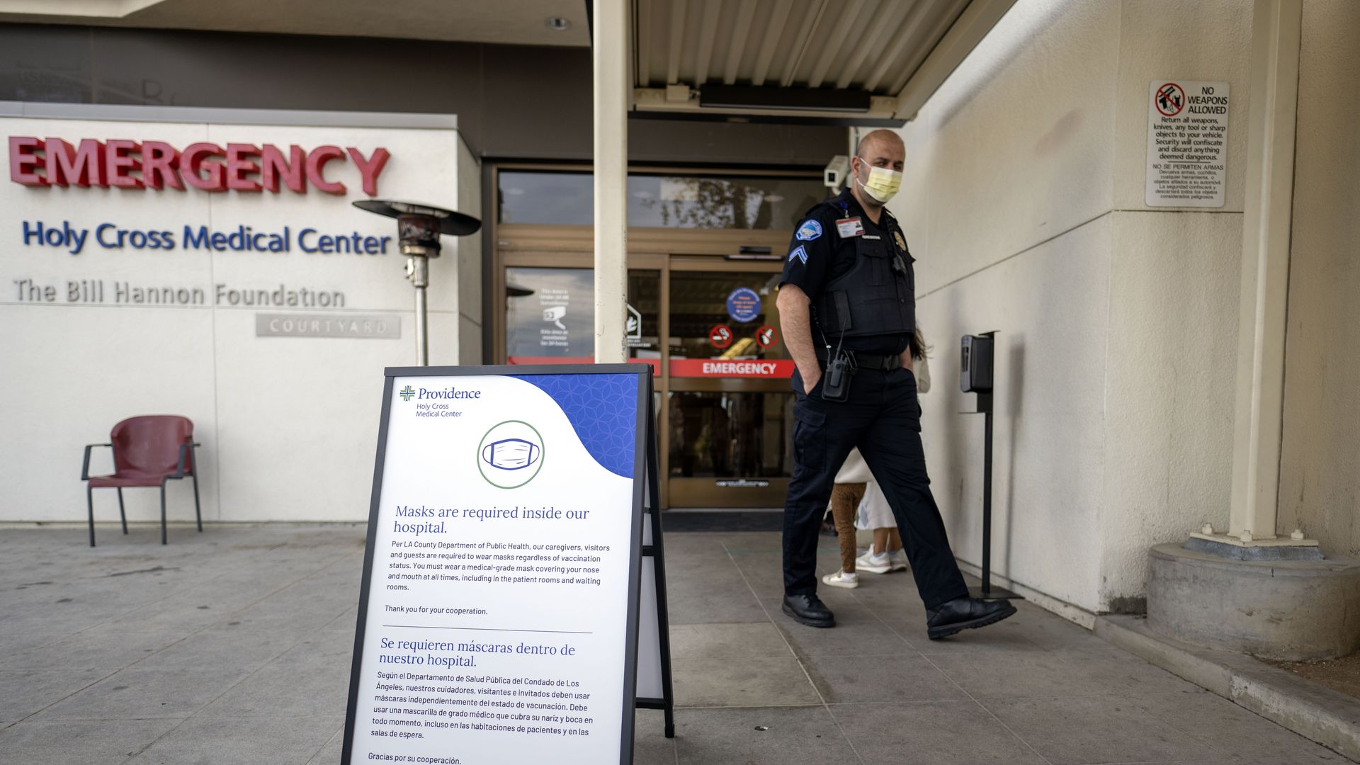 A photo of a worker in a mask outside a hospital.