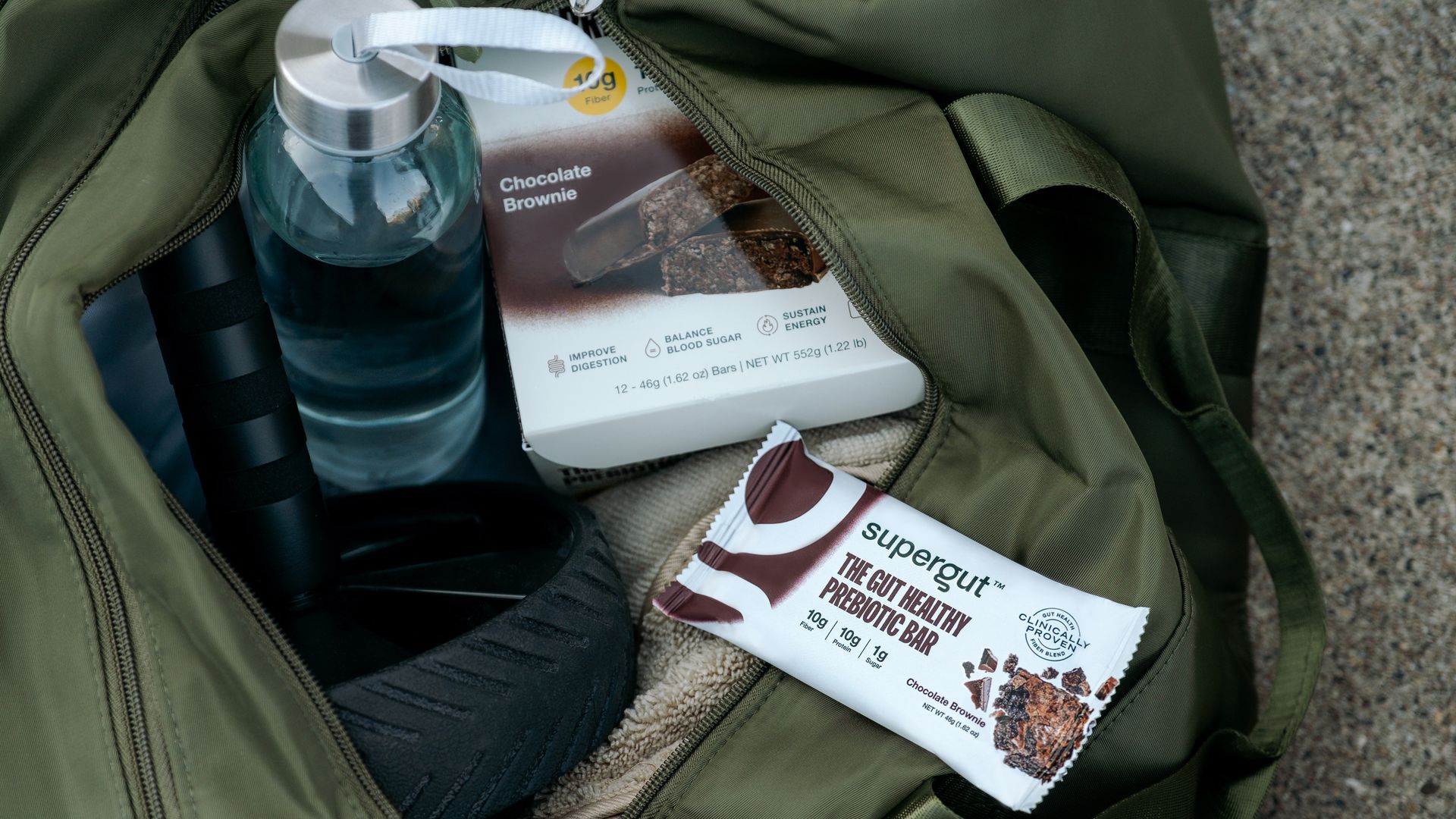 SuperGut branded pre-biotic bar rests on top of a green duffle bag.