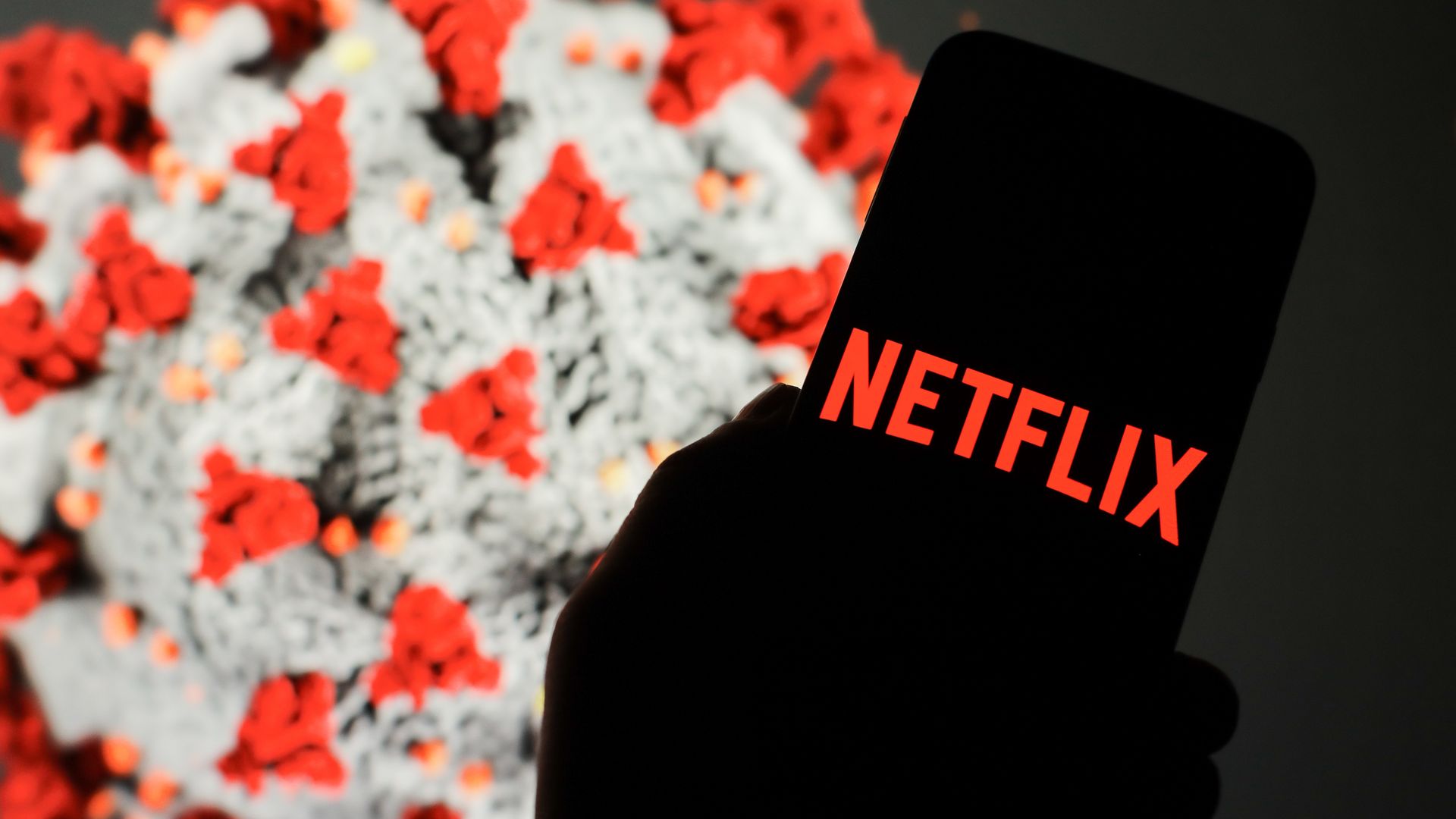 Illustration a Netflix logo seen displayed on a smartphone with computer model of the COVID-19 coronavirus in the background