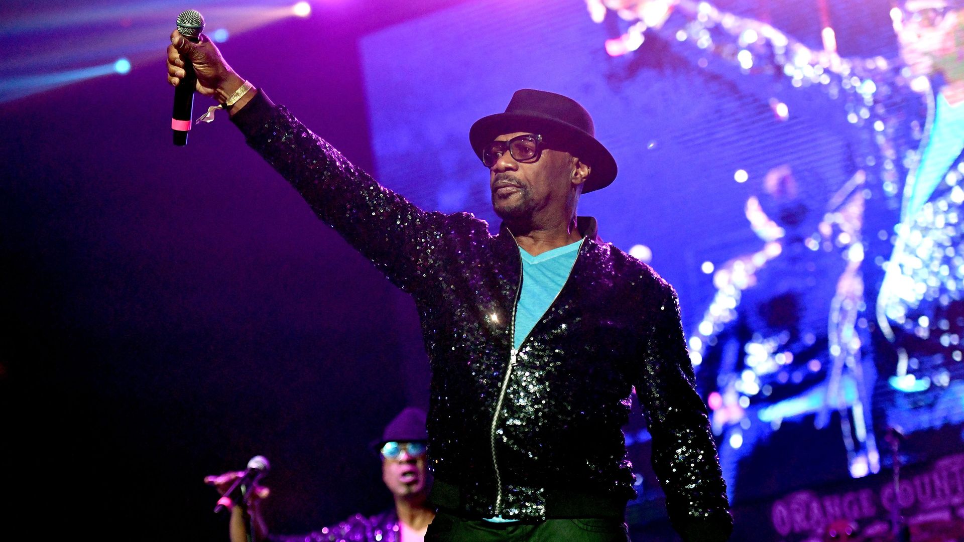 Singer Bobby Harris raises a microphone on stage during a performance. 