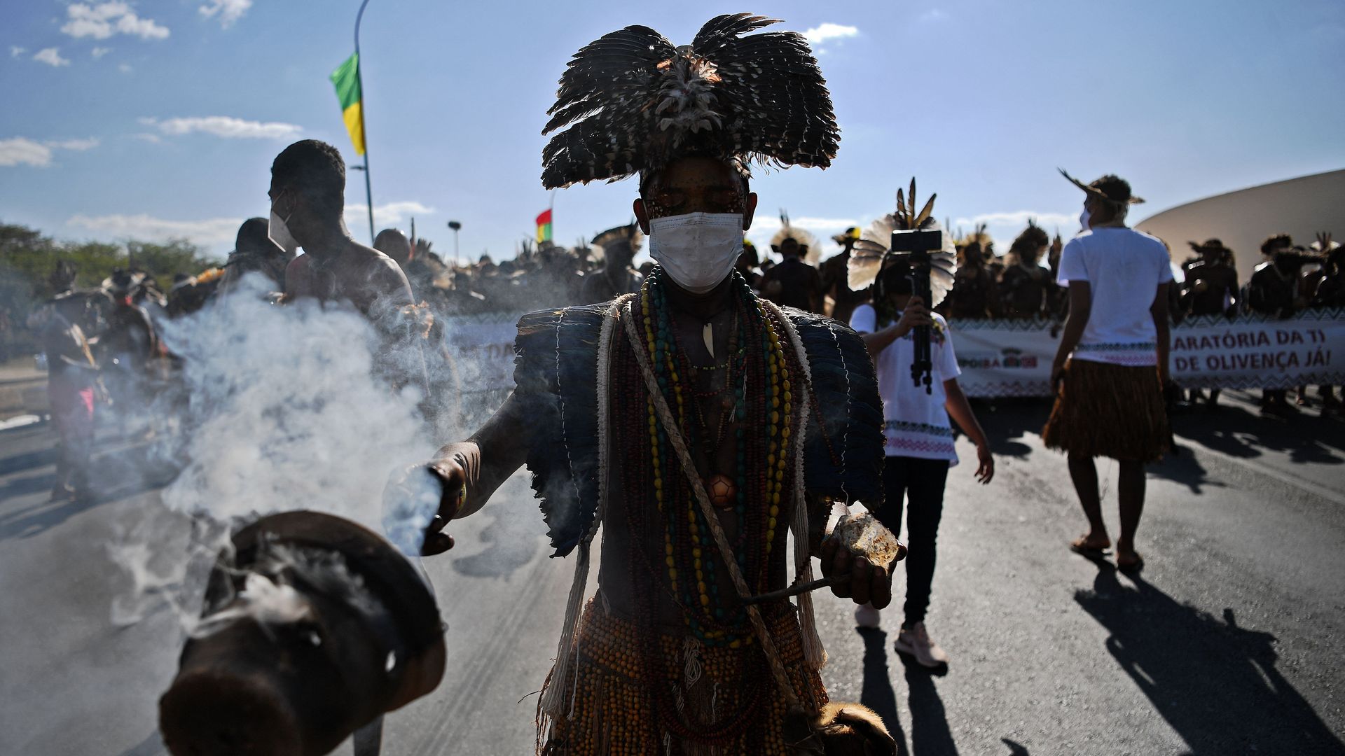 Photo of an Indigenous person burning incense and leading a crowd of protesters