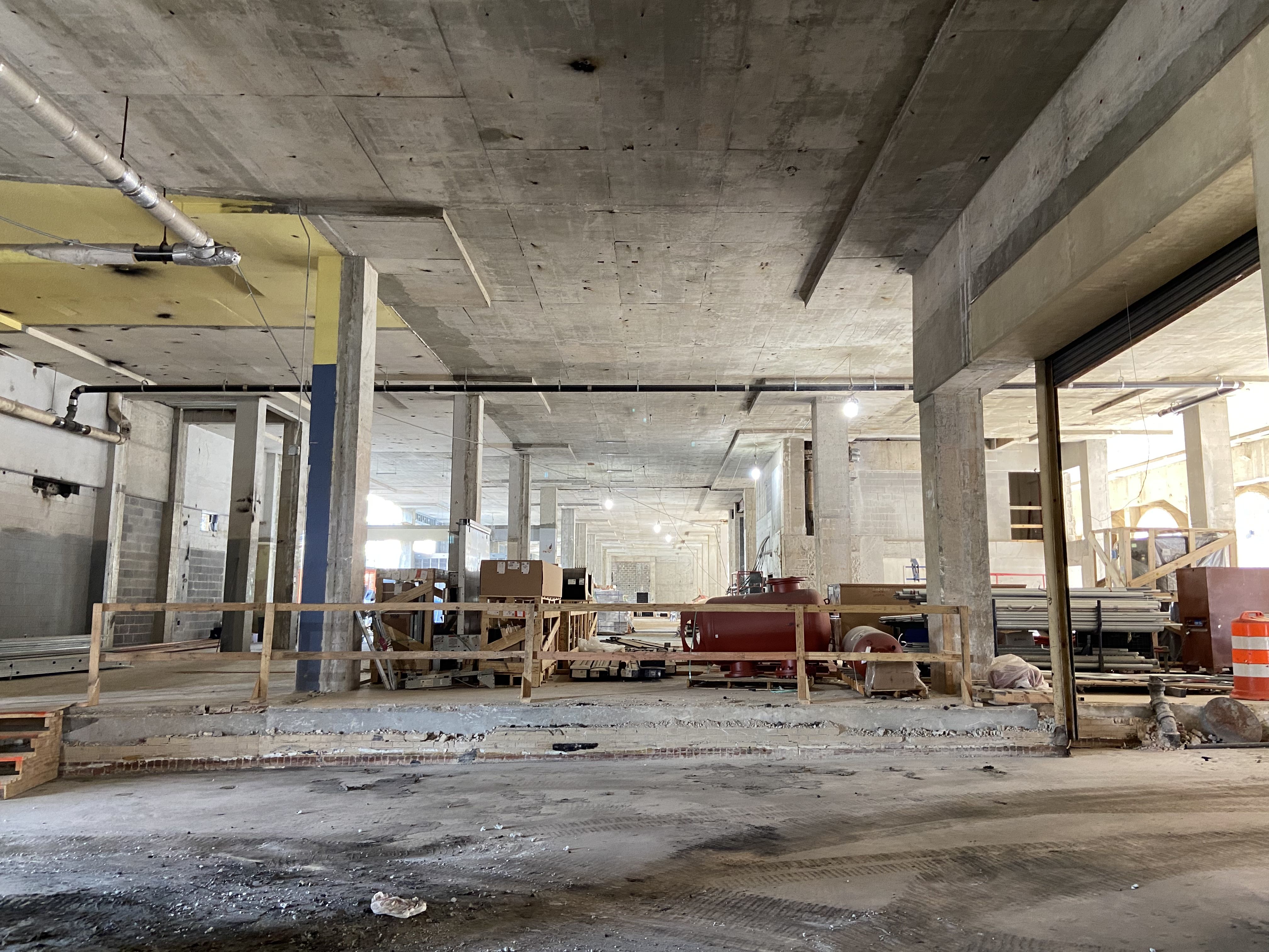 The interior of a building with high ceilings under construction with exposed concrete