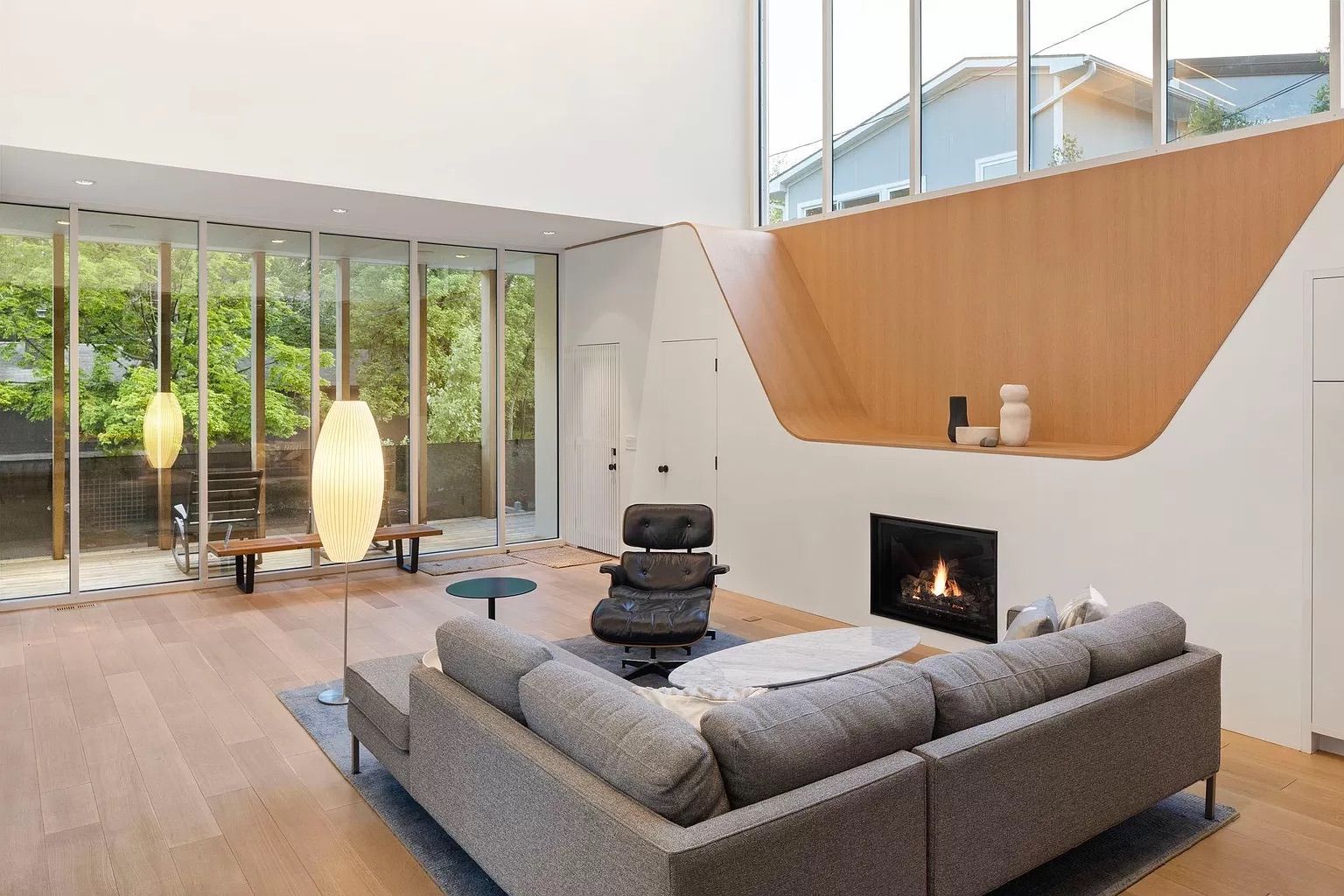 A living room with a gray couch and white paint and glass walls.