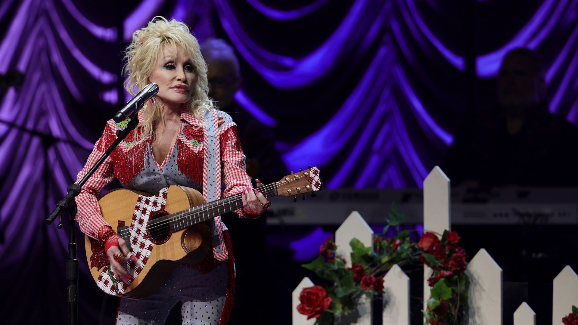 Dolly Parton performs holding a guitar