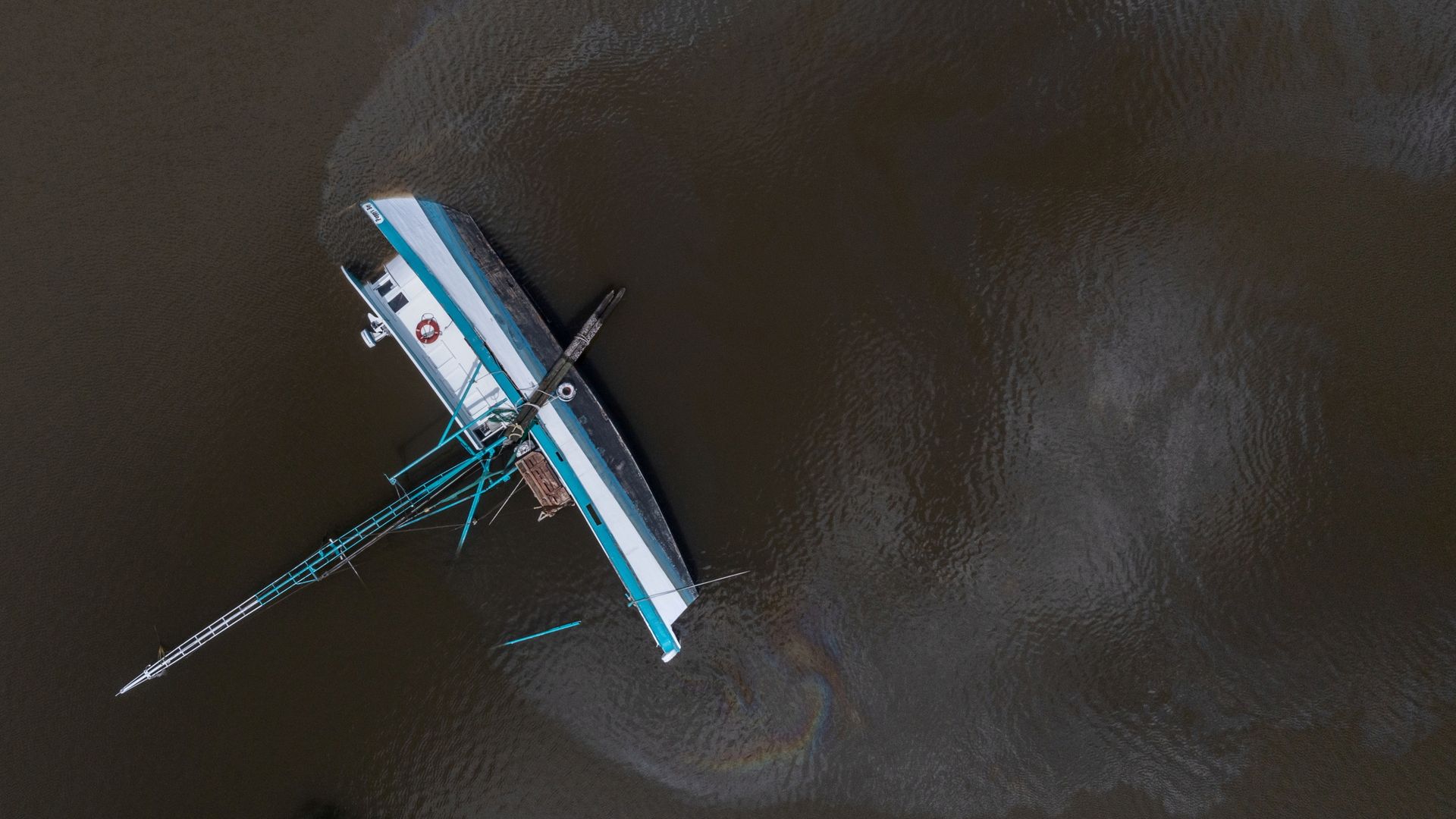 Fuel leaks from a capsized boat along Bayou Lafourche in the aftermath of Hurricane Ida