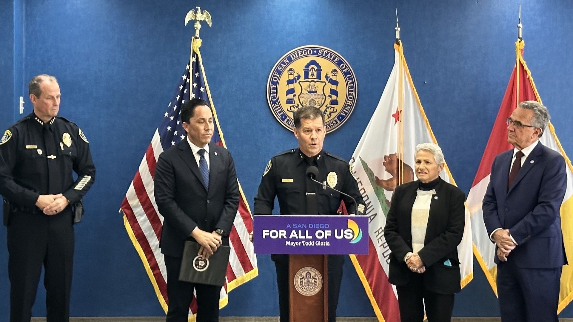The new San Diego police chief stands at a podium with other government officials behind him. 