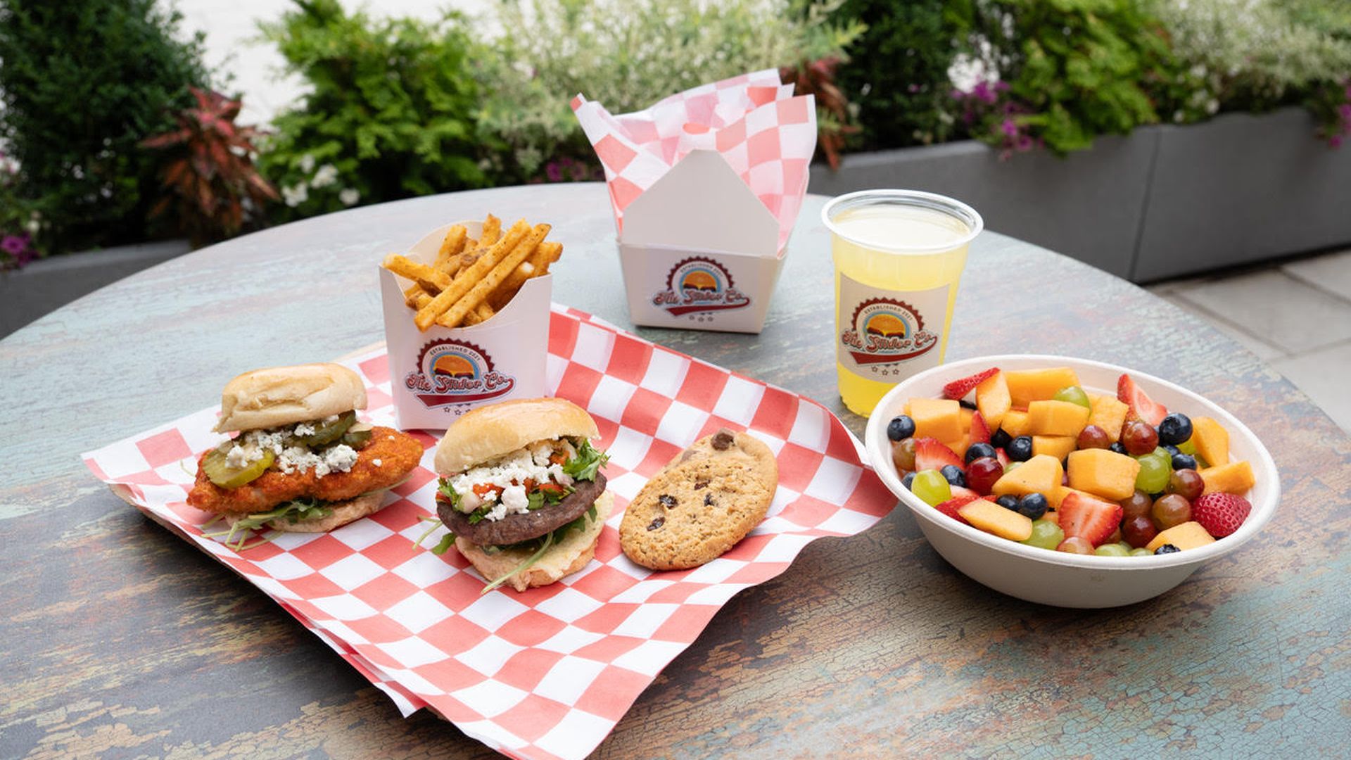 A picture of the Slider Co. food offerings, including chicken and angus beef sliders, cookies, drinks and fruit salad.