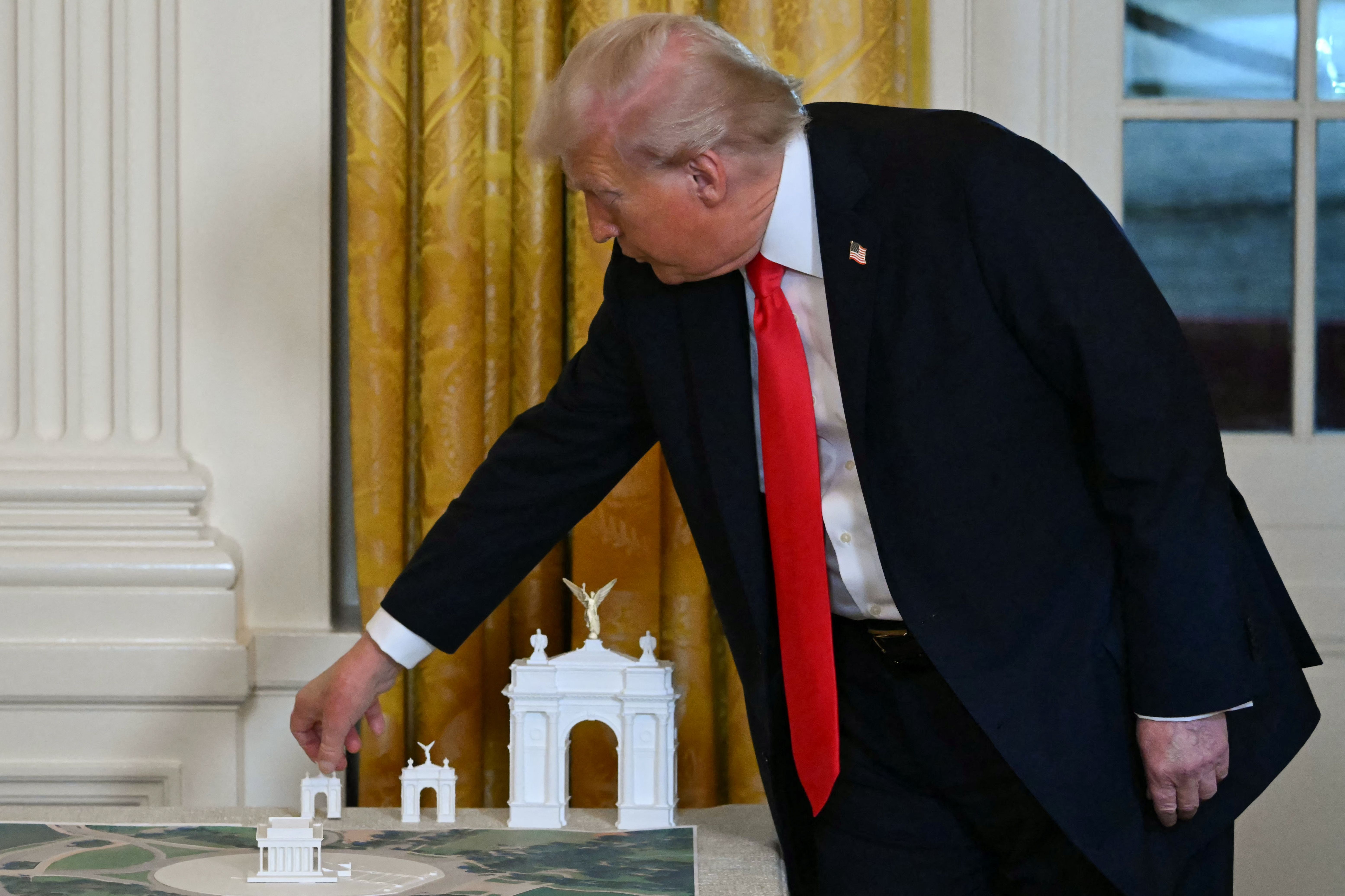President Trump displays three models of an arch he wants to build near Arlington National Cemetery last month.