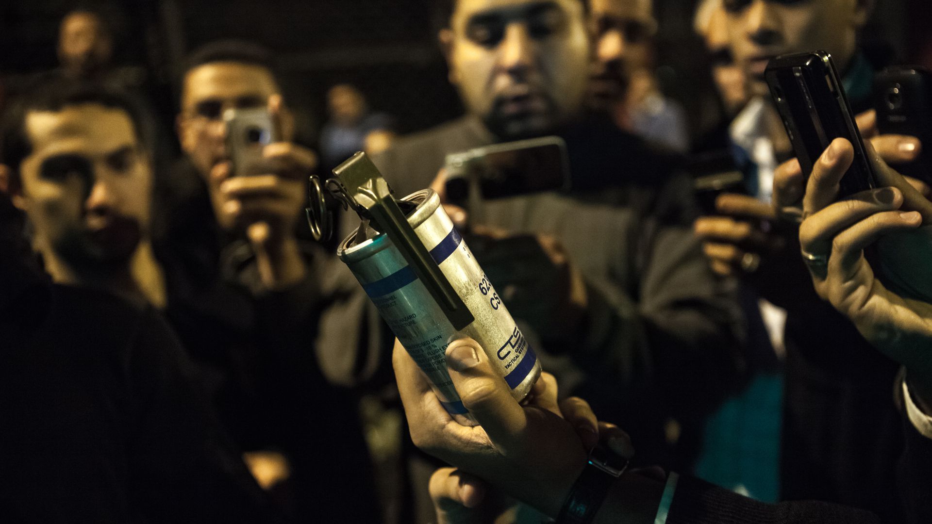 Protestor holding up a canister of tear gas