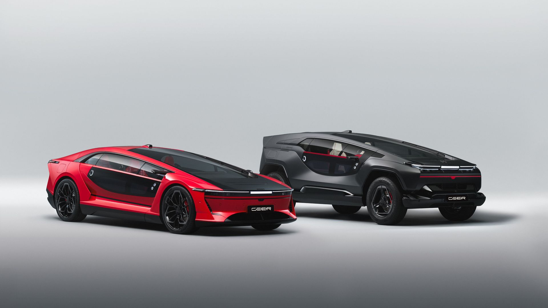 Two futuristic cars sit side by side on a pale backdrop: a red, low-slung coupe with black accents on the left, and a dark gray/black SUV with red trim on the right. The cars are made by CEER, a new Saudi Arabian company.