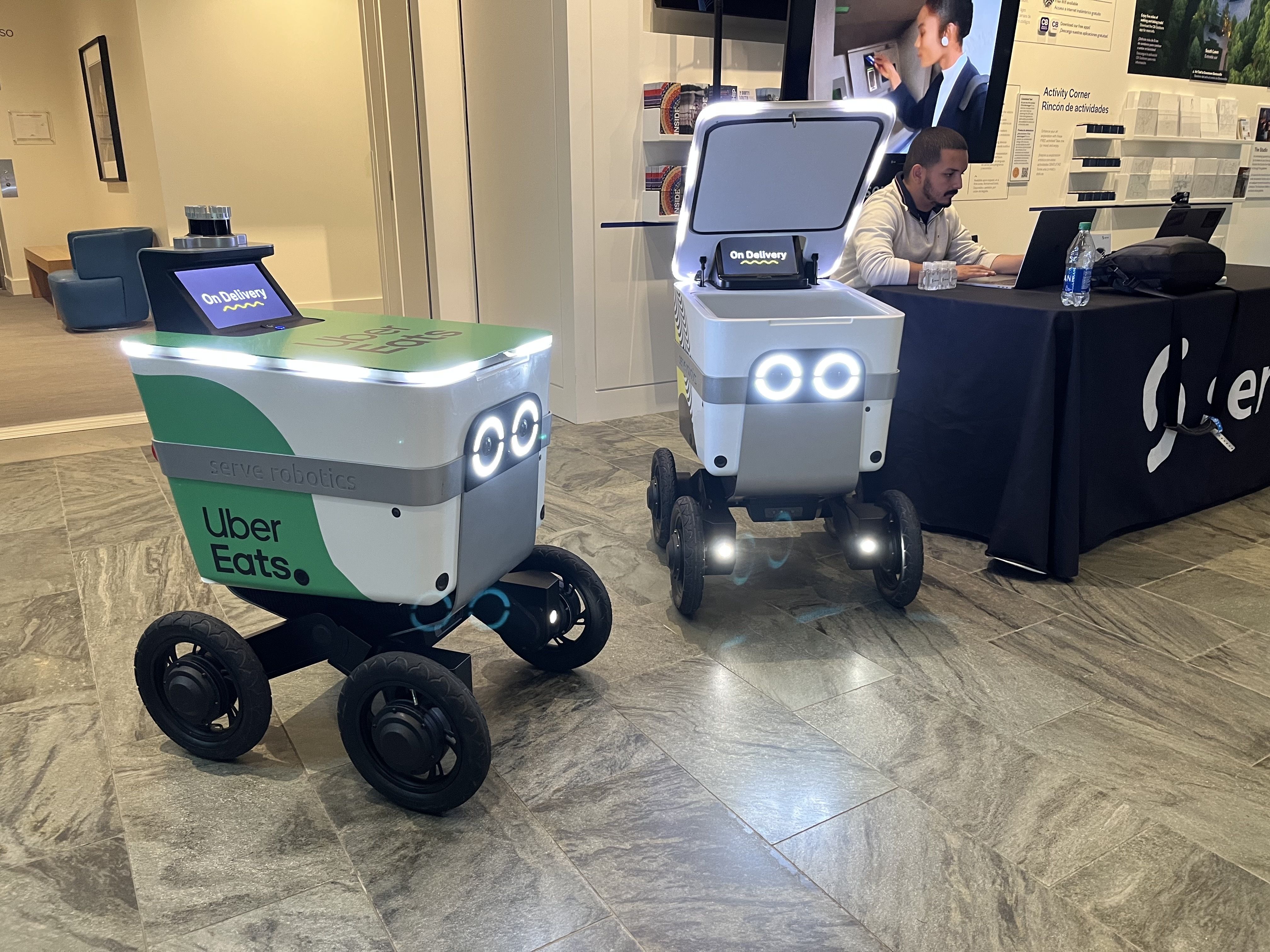 Self-driving delivery robots await packages to deliver.