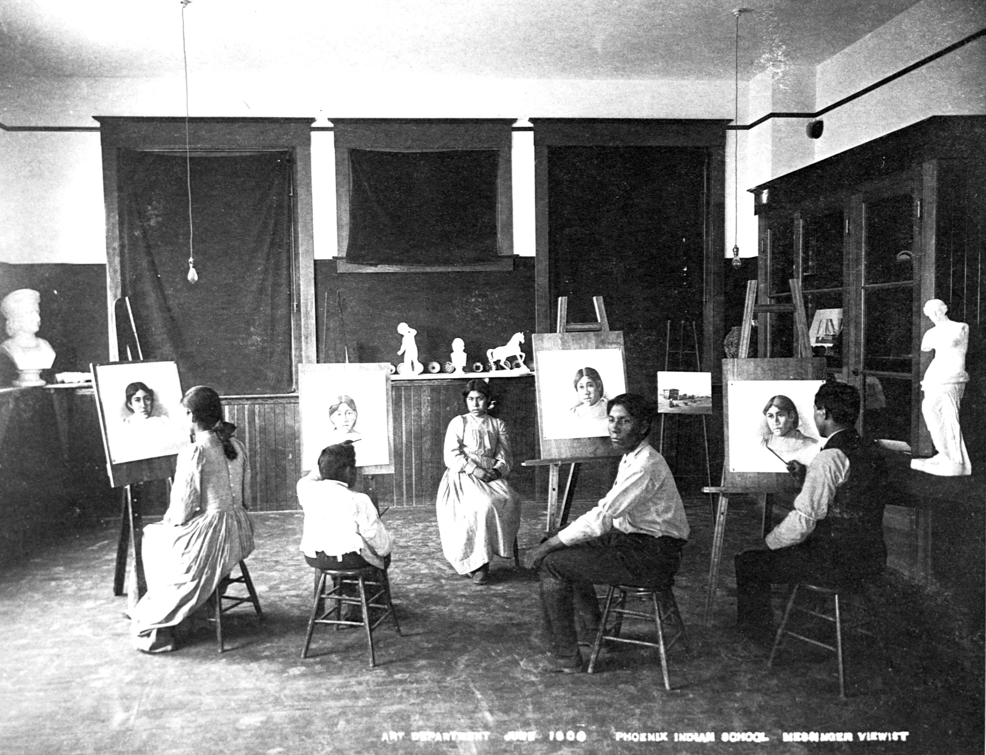 A black-and-white photo of students posing with paintings. 