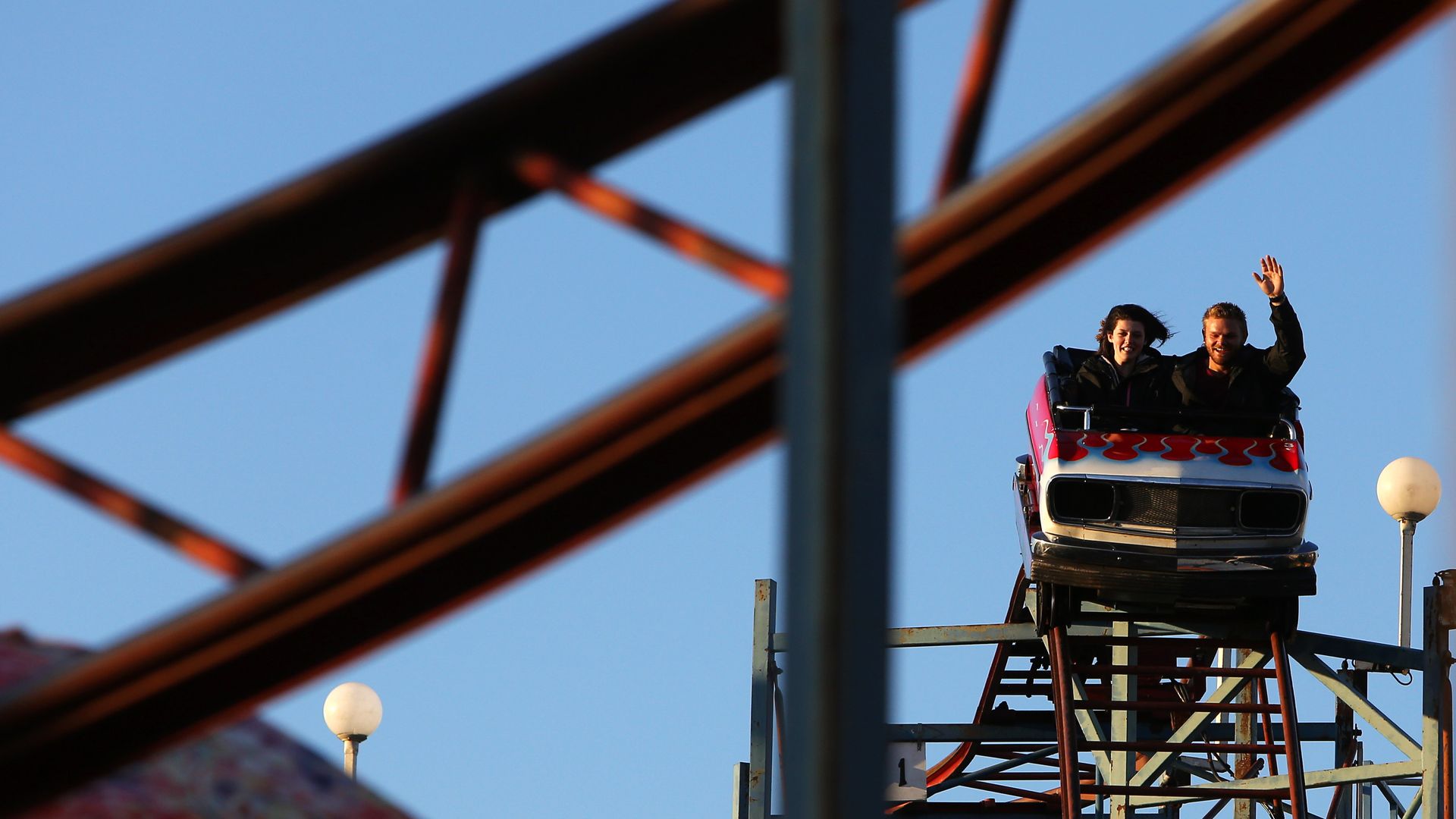 People on a roller coaster are photographed through the bars on the ride. 