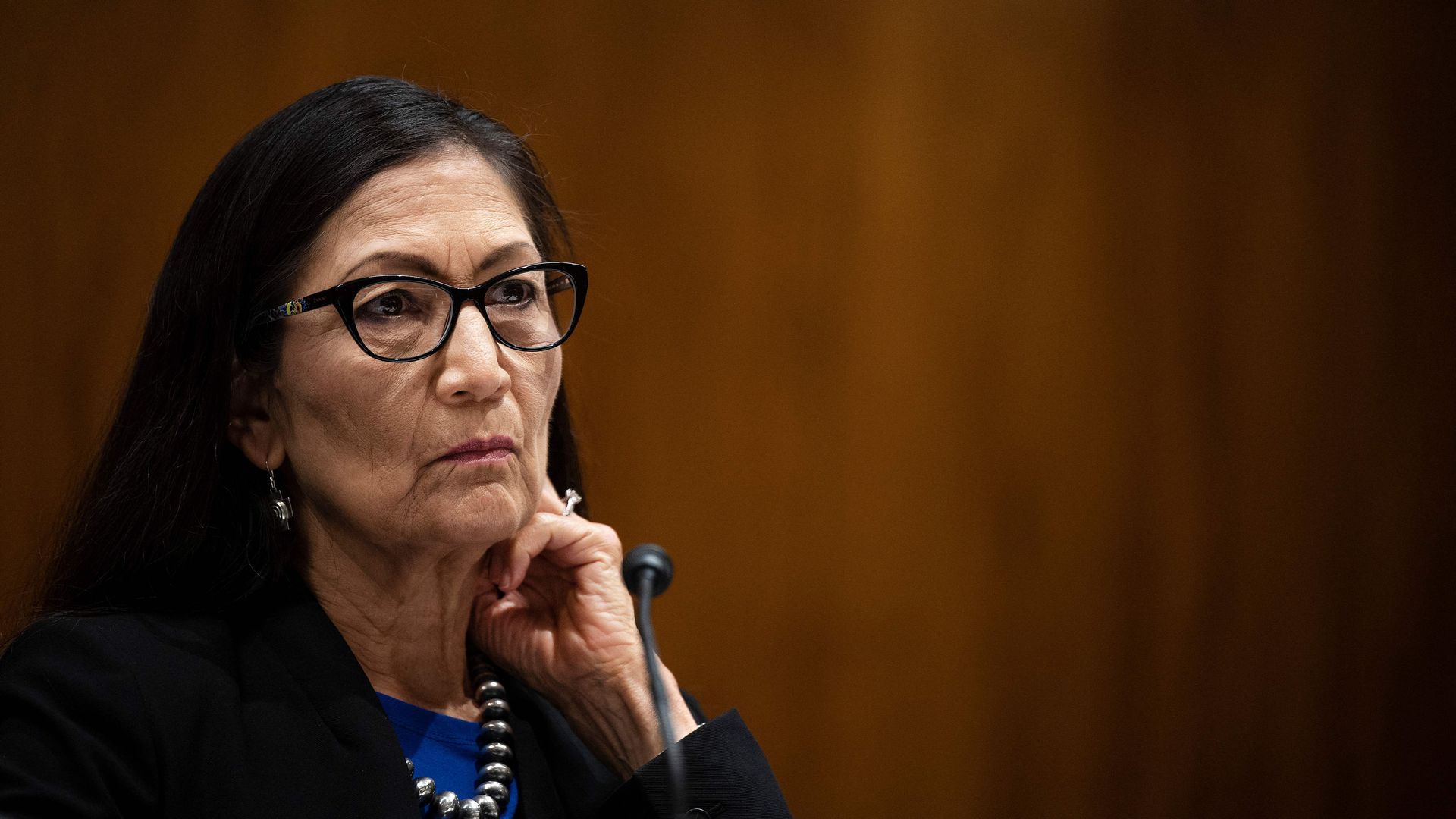 Photo of Deb Haaland with a hand raised to her cheek