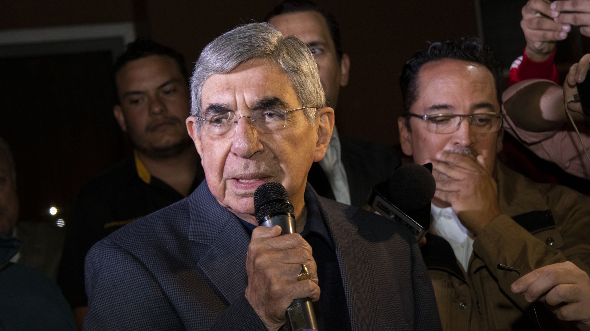 Oscar Arias speaks into a microphone during a demonstration.