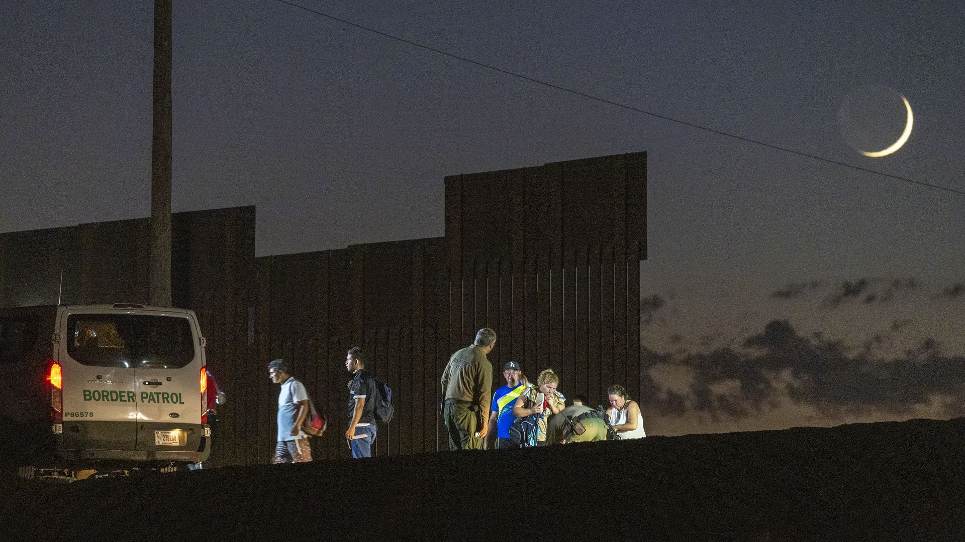 Border patrol agents take people into custody next to the U.S.-Mexico border fence where the last of the Colorado River flows into Mexico