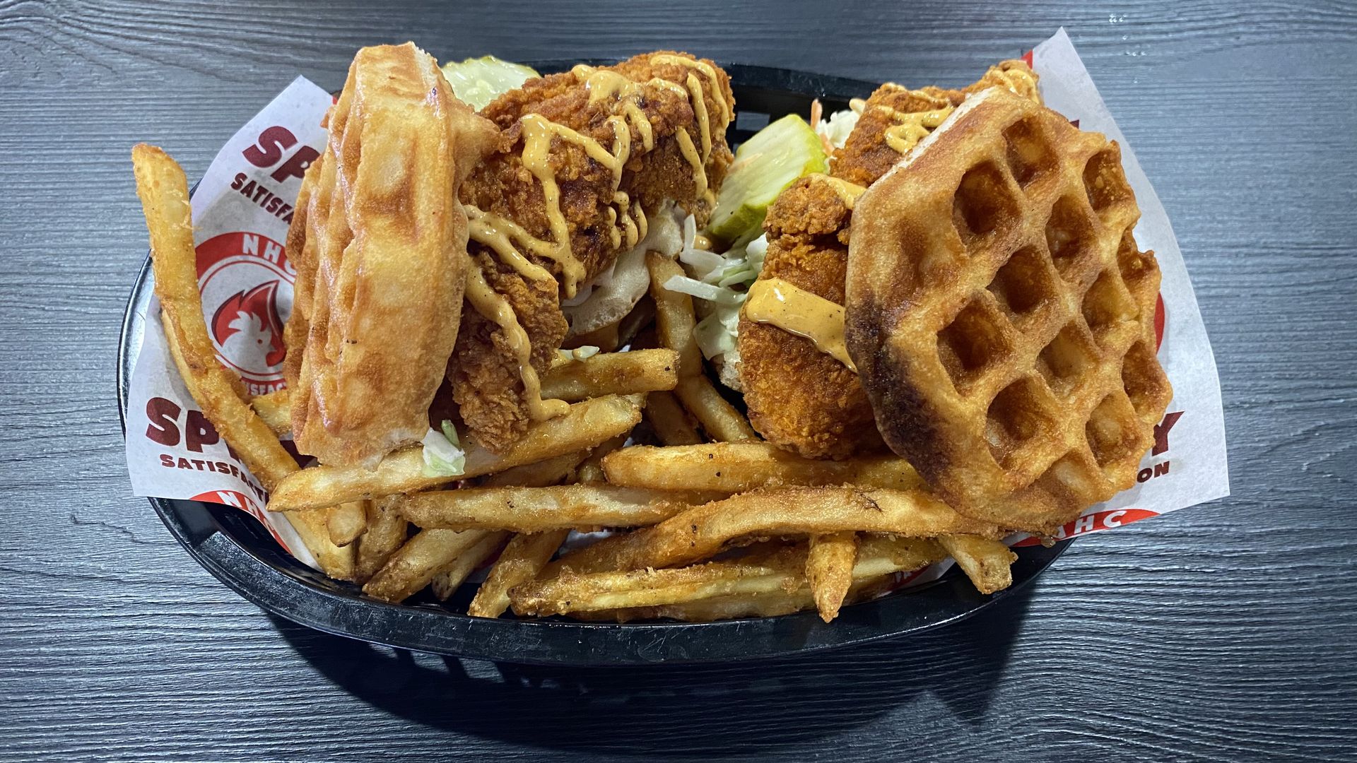 Fried chicken waffle sandwiches in a basket with French fries. 