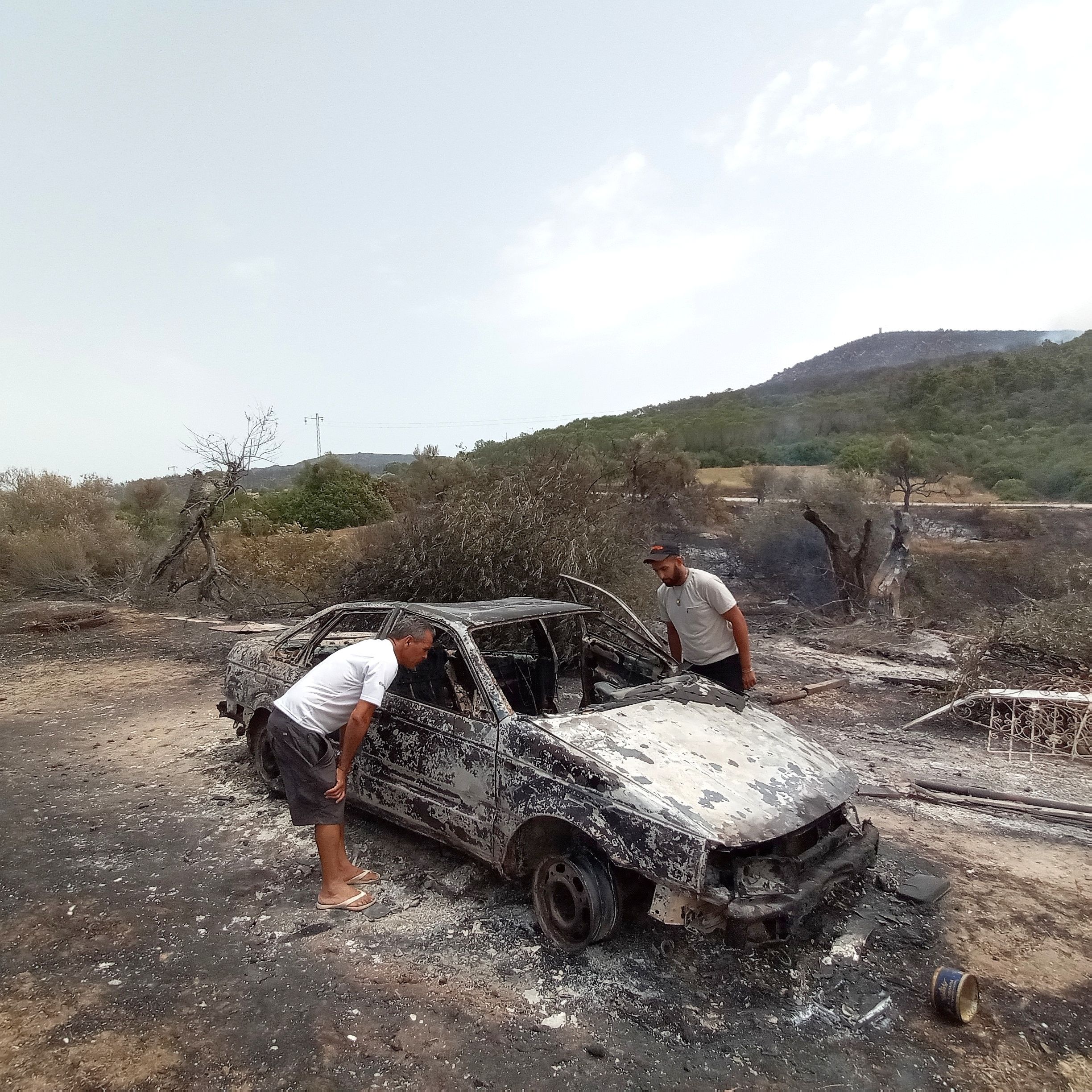 People look the burnt car during wildfire in Jendouba, Tunisia on July 25, 2023. 450 hectares of forested areas were damaged due to wildfire on since July 12. 