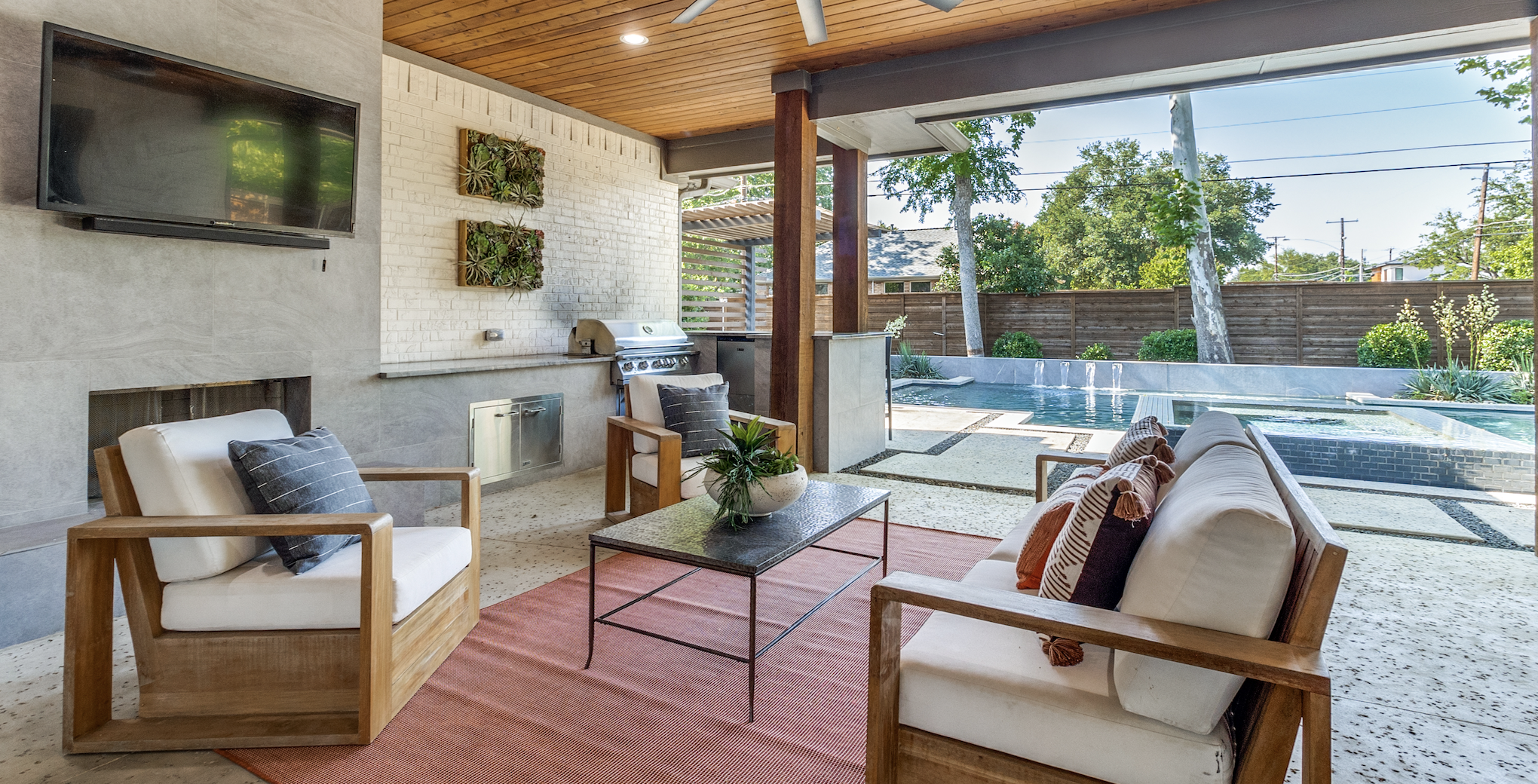A outdoor seating area, with chairs and a TV, overlooking a pool