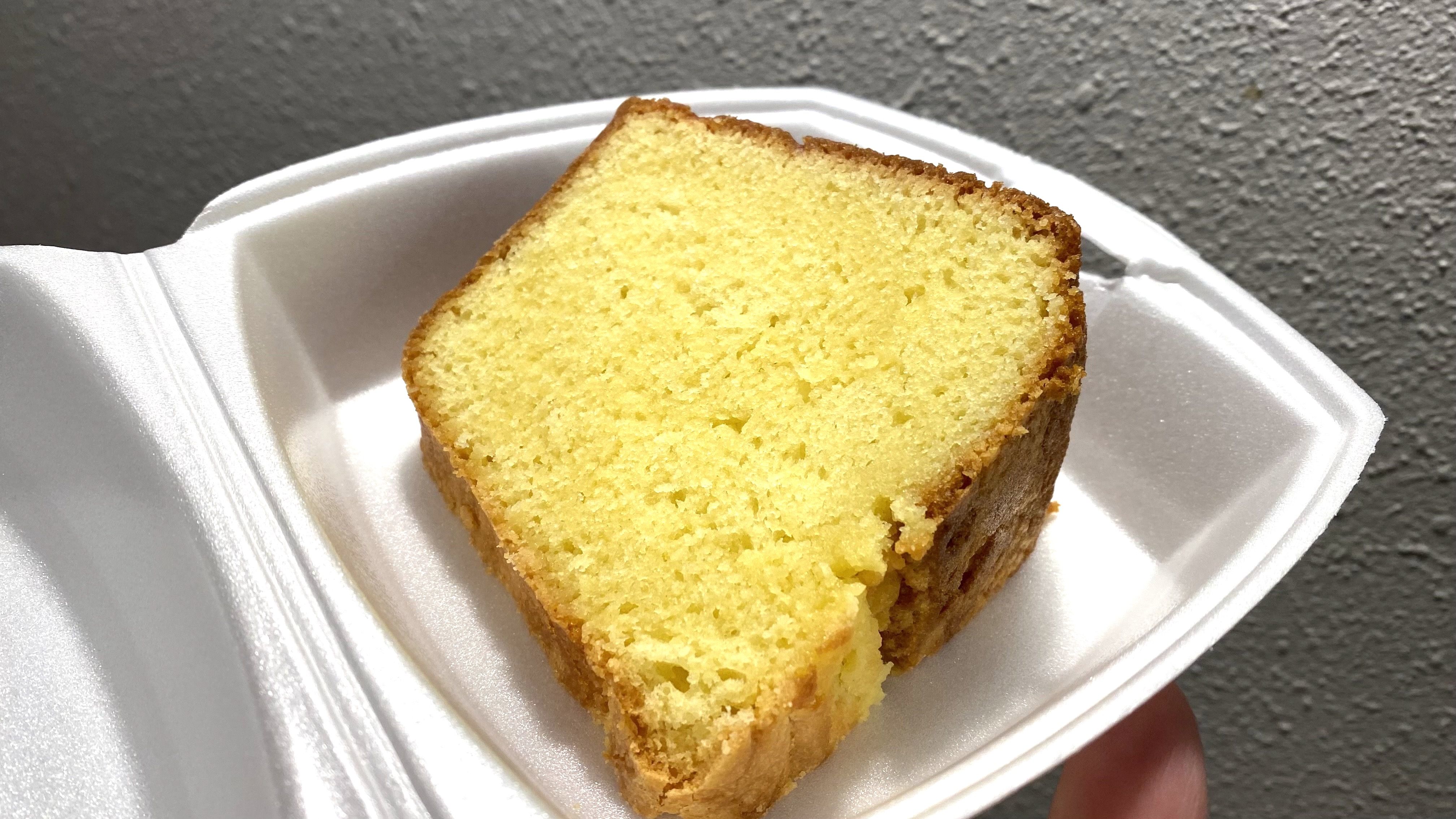 A photo of a large slice of pound cake in a to-go container.