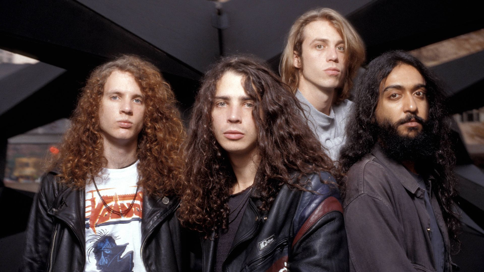 Members of Soundgarden stand in a group looking at the camera wearing leather coats and oversized shirts over t-shirts. All have long hair. It's 1989.