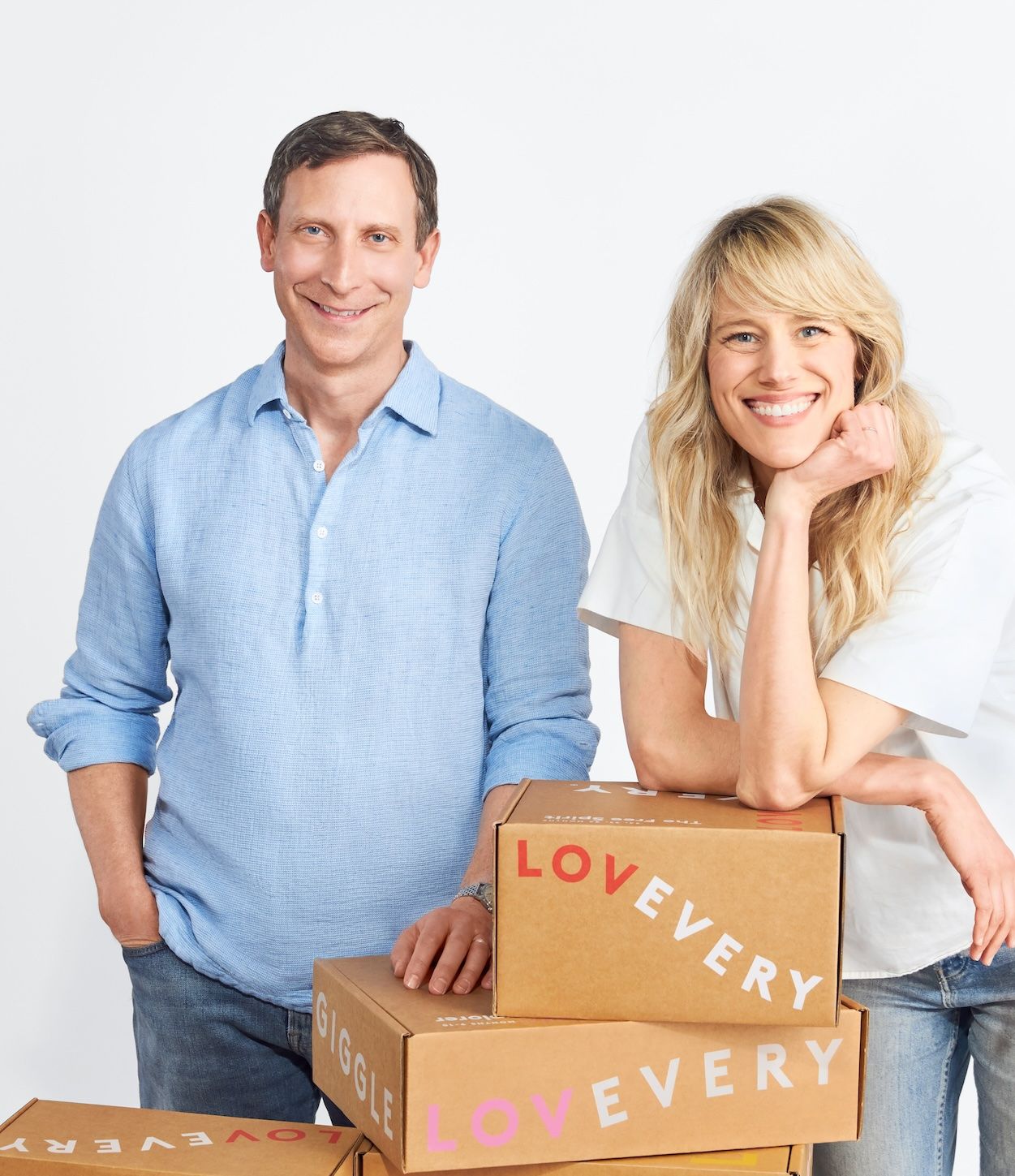A headshot of a man and a woman. They are posing with cardboard boxes.