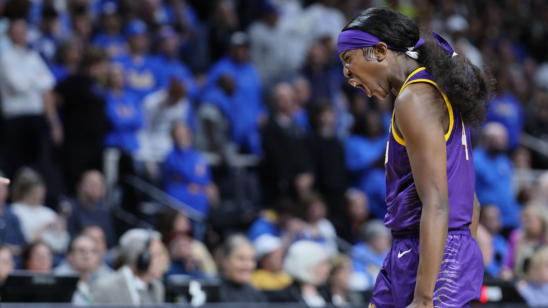 Flau'Jae Johnson walks across the basketball core, looking down and curling both hands into fists as she shouts in victory.