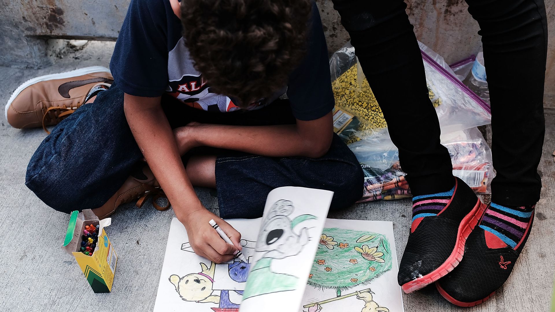A Honduran child draws while waiting with his family after being denied entry into the Texas city of Brownsville which has become dependent on the daily crossing into and out of Mexico.