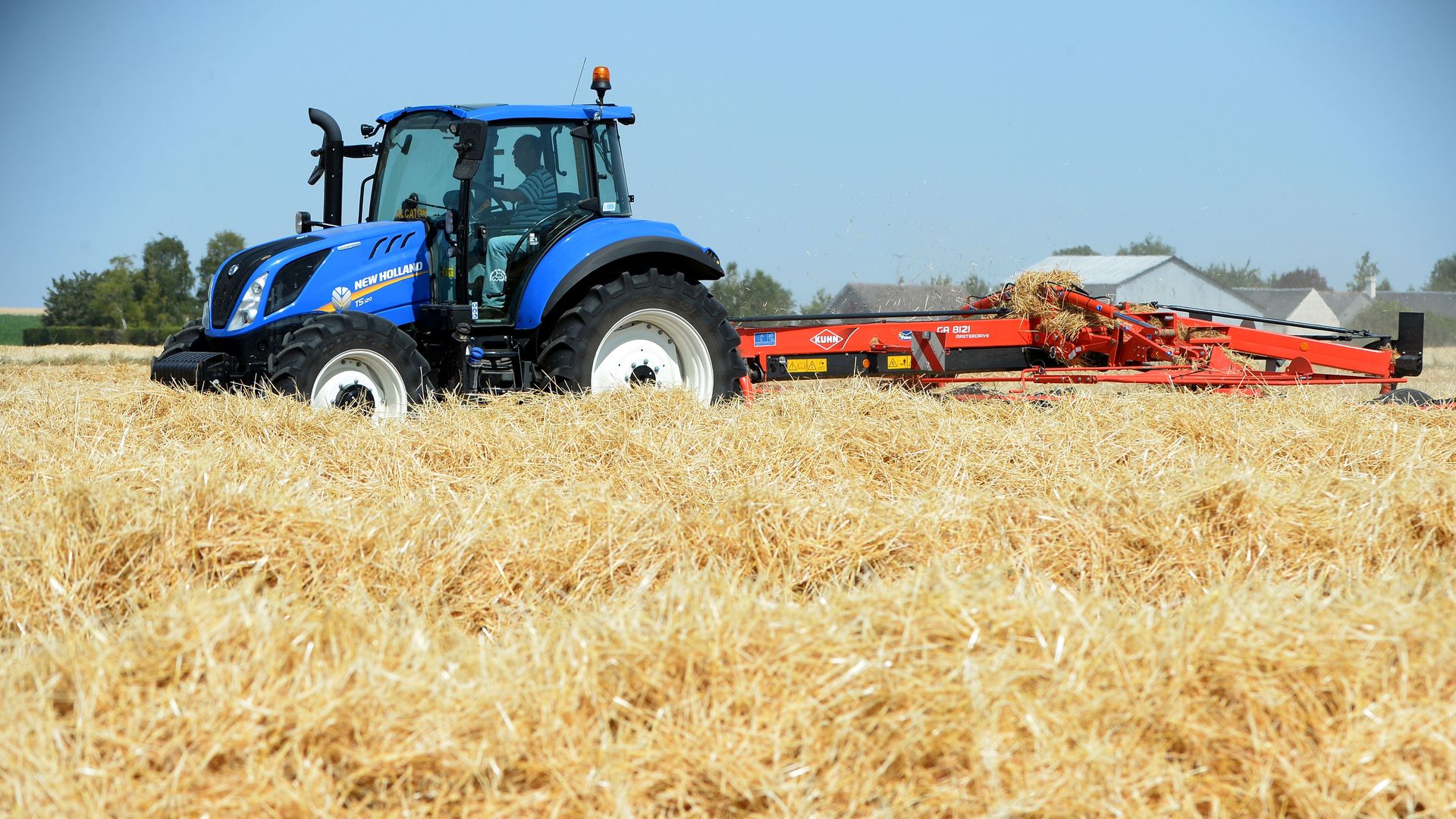 A tractor in the middle of biles of hay. 