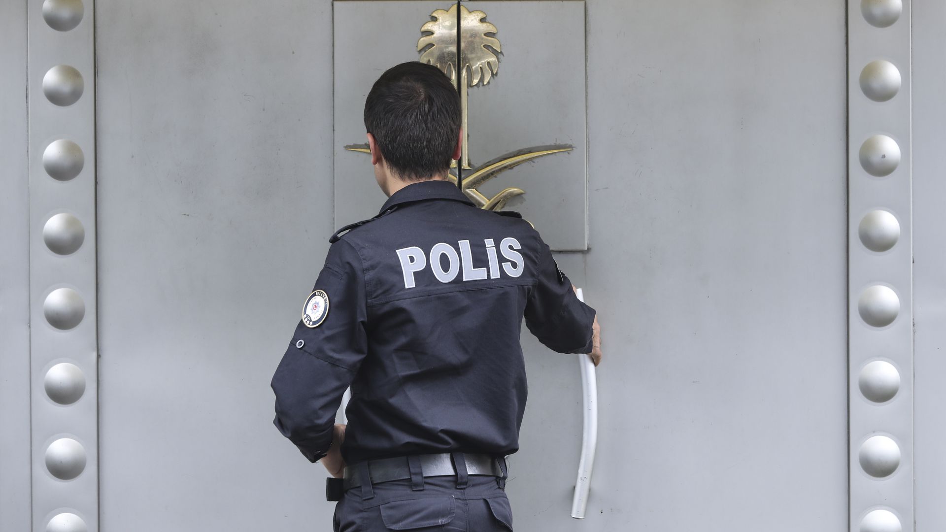 A Turkish police officer providing security enters the Saudi Arabia's consulate as they check papers of a man on October 12, 2018 in Istanbul, Turkey.