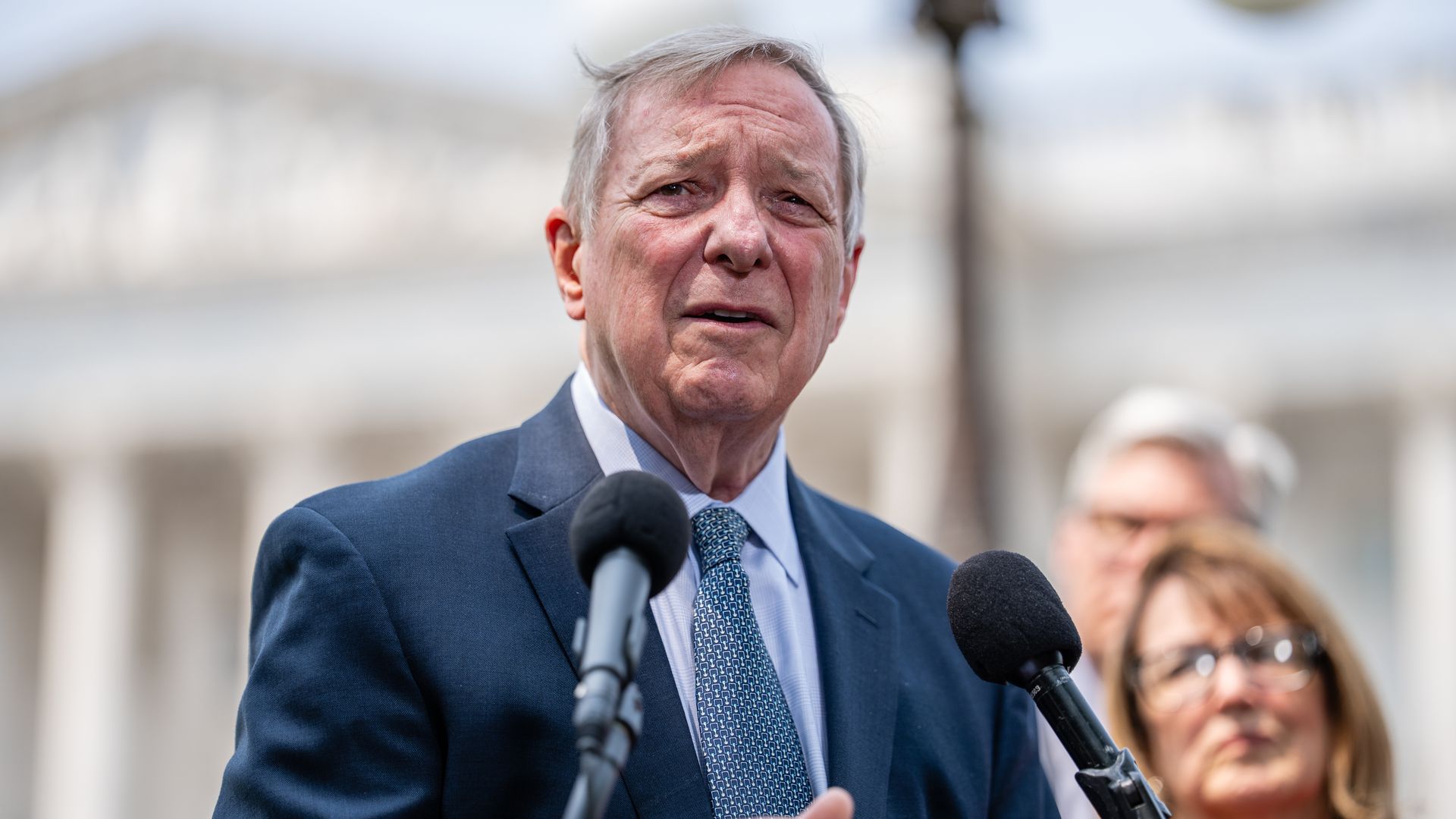 Photo of a man behind a podium speaking. 