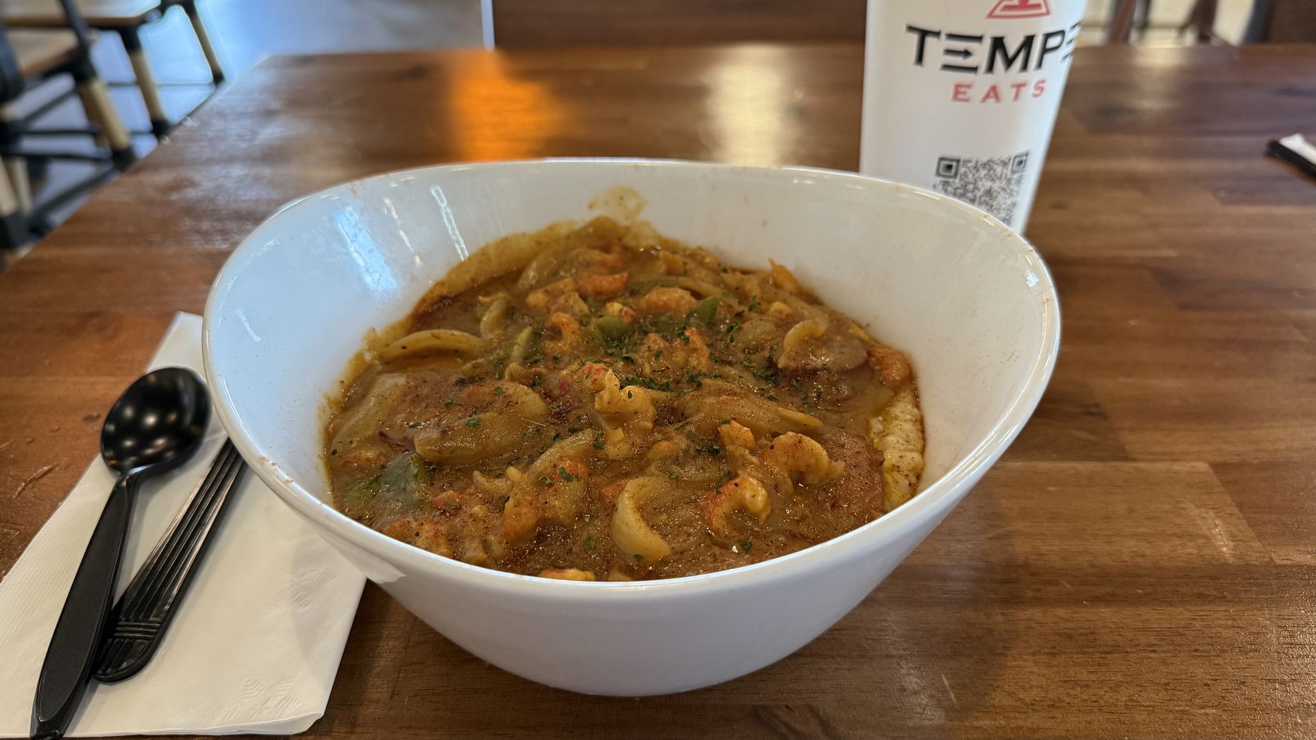 A white bowl filled with crawfish etouffee over rice.