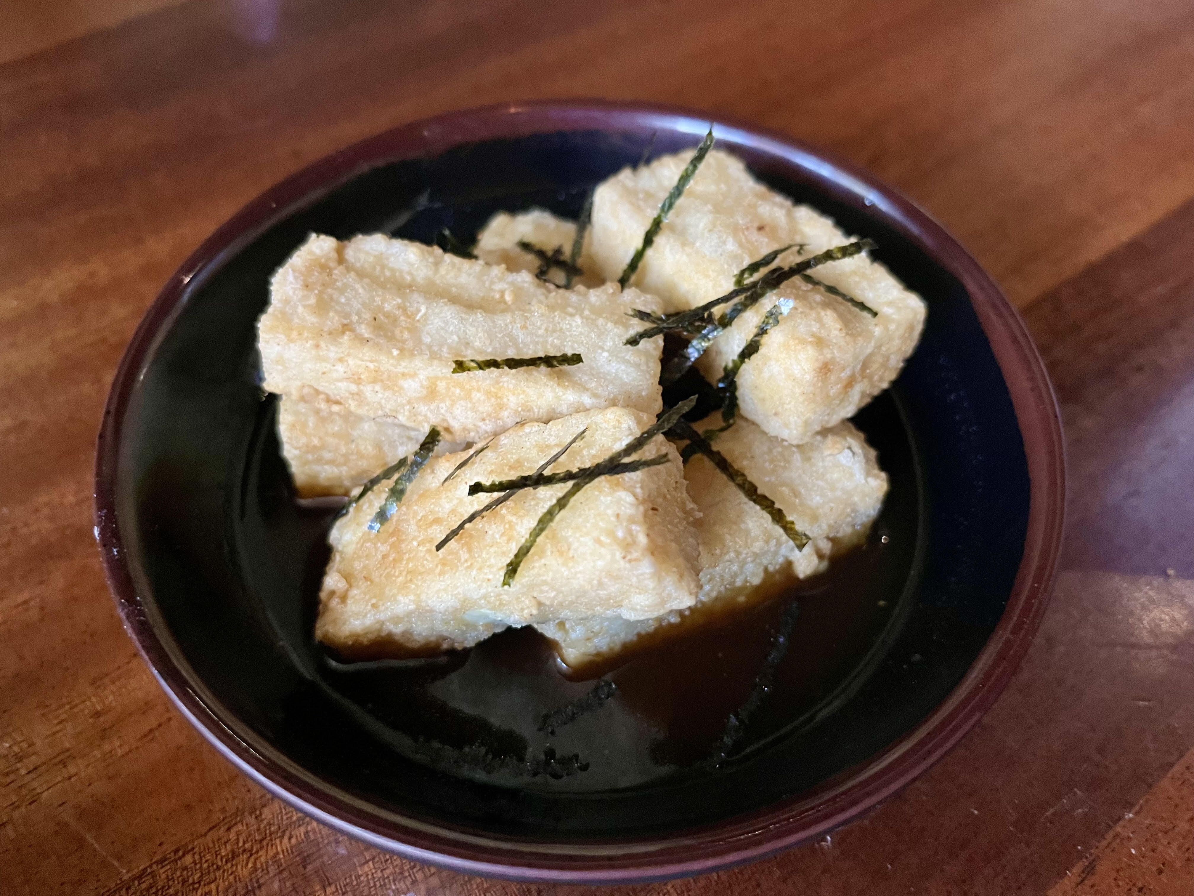 A pile of battered tofu on a dark plate. 