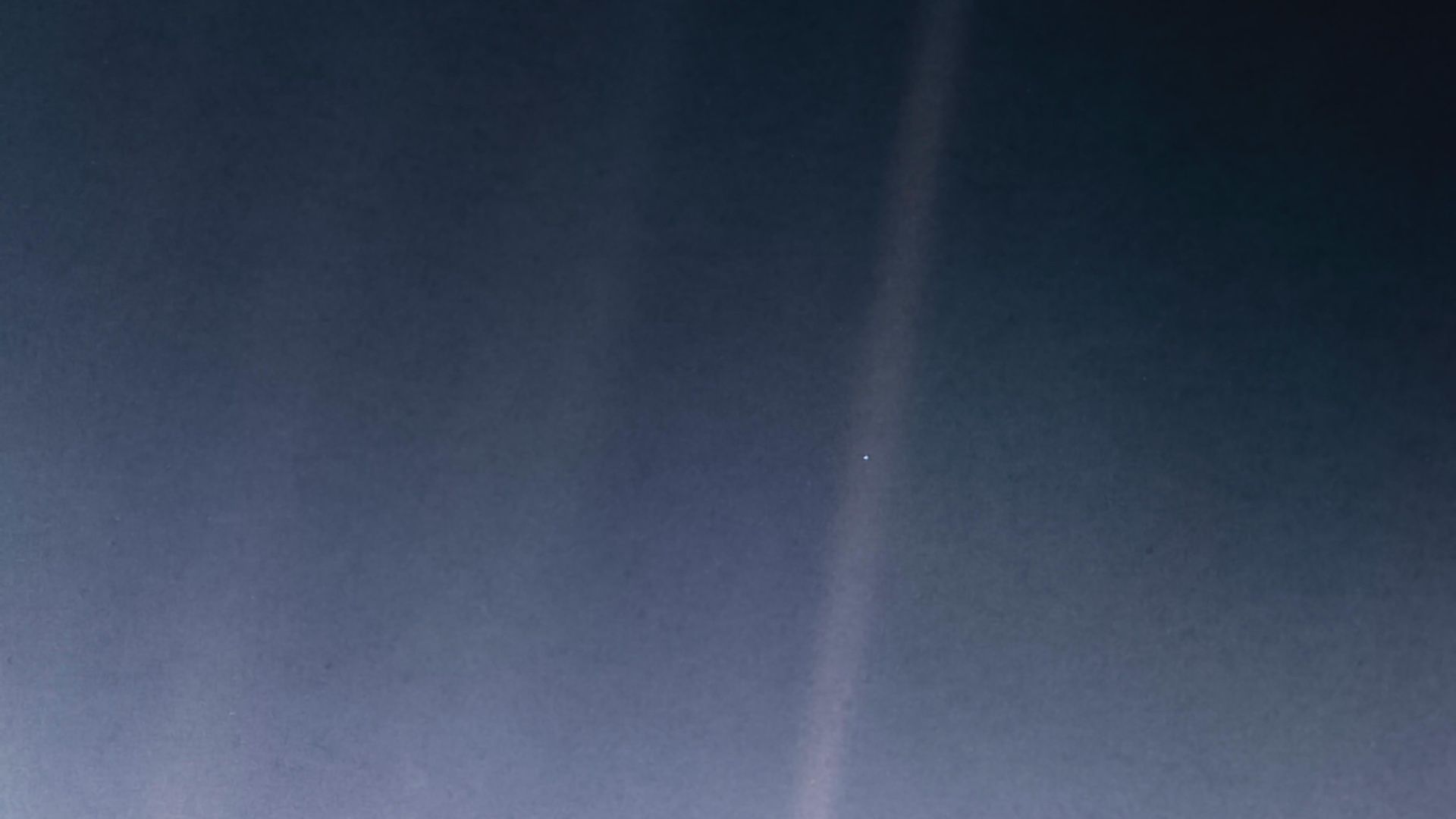 Streaks of light with a small pinpoint of light, the Earth, suspended in one of the sunbeams