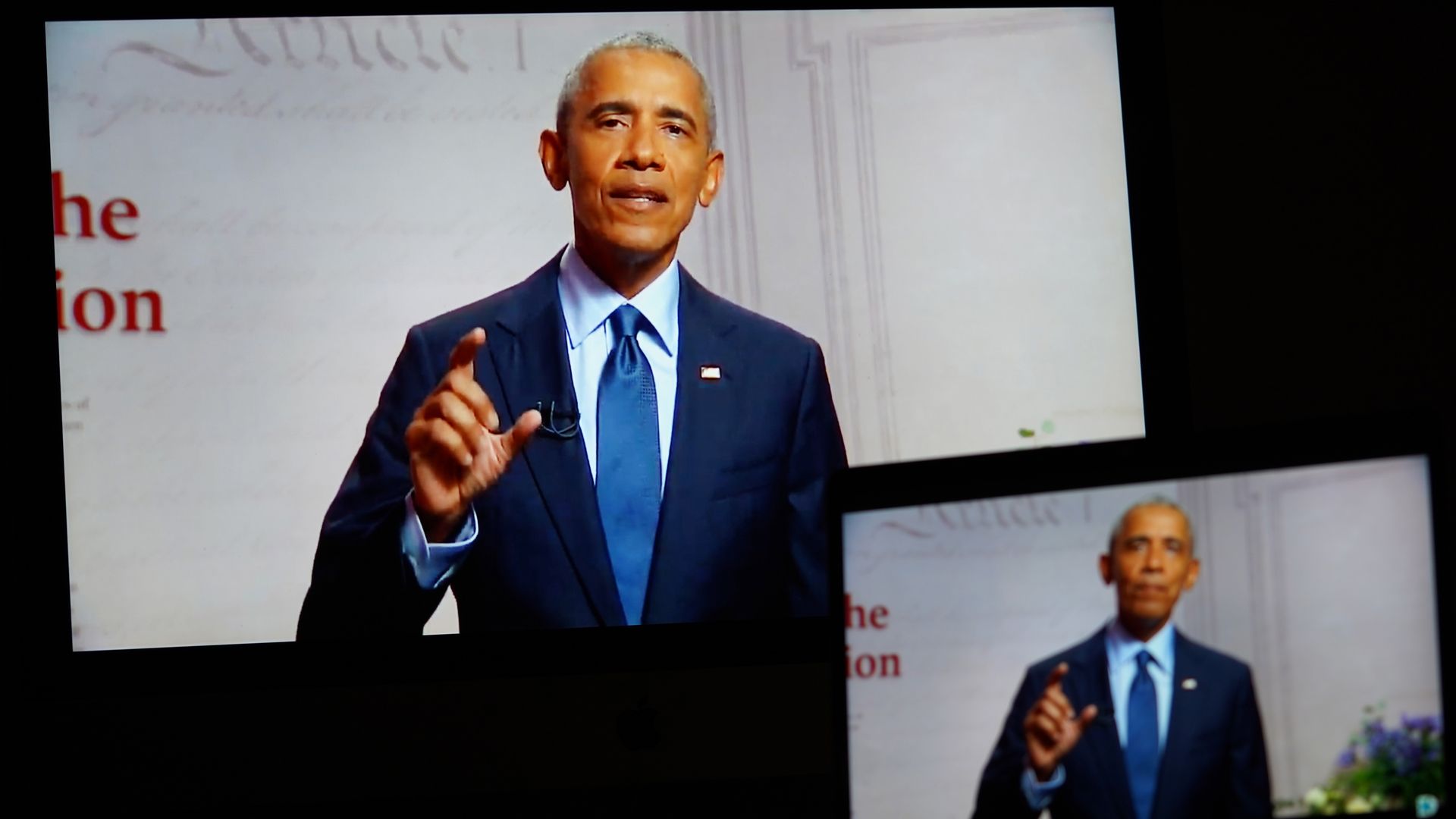 Two screens showing Obama as he speaks