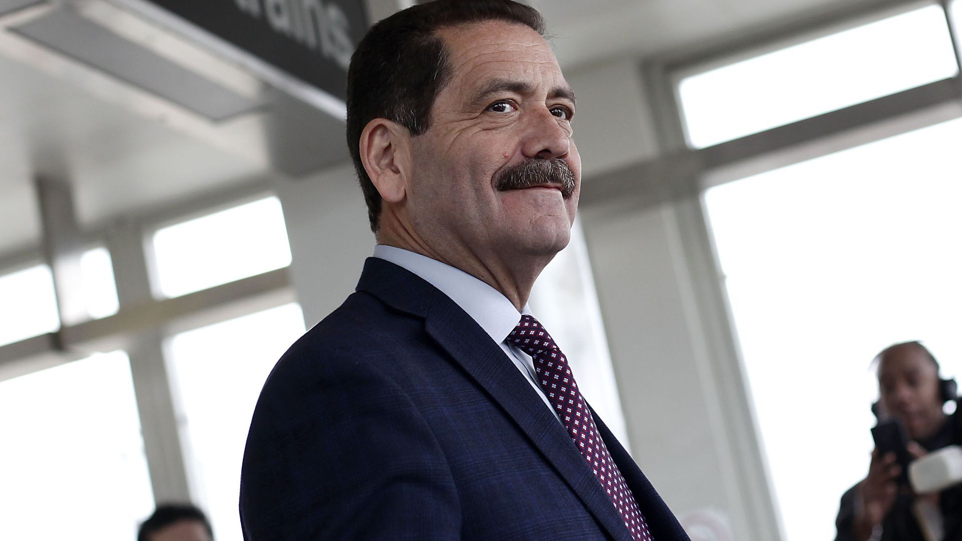  Jesús "Chuy" García smiles while wearing a dark blue suit and a red patterned tie.