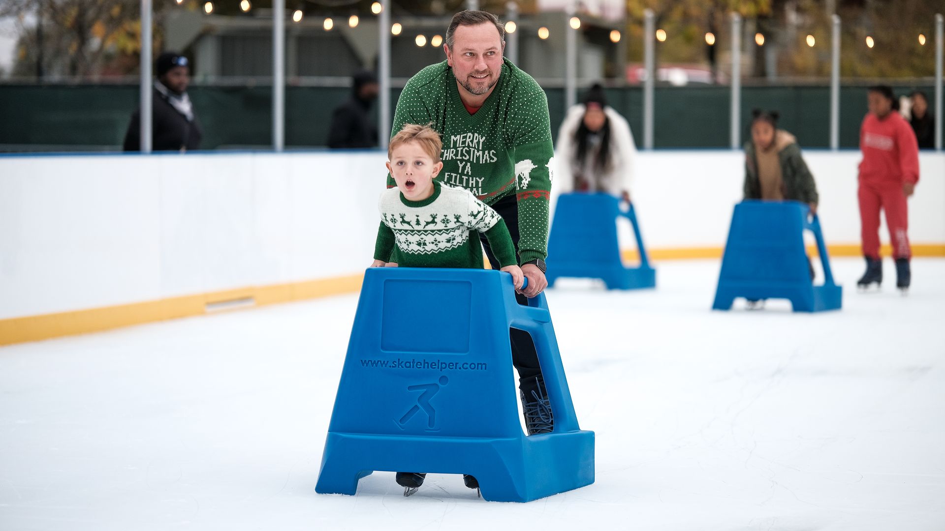 A father and son ice skating at the rink at City Springs.