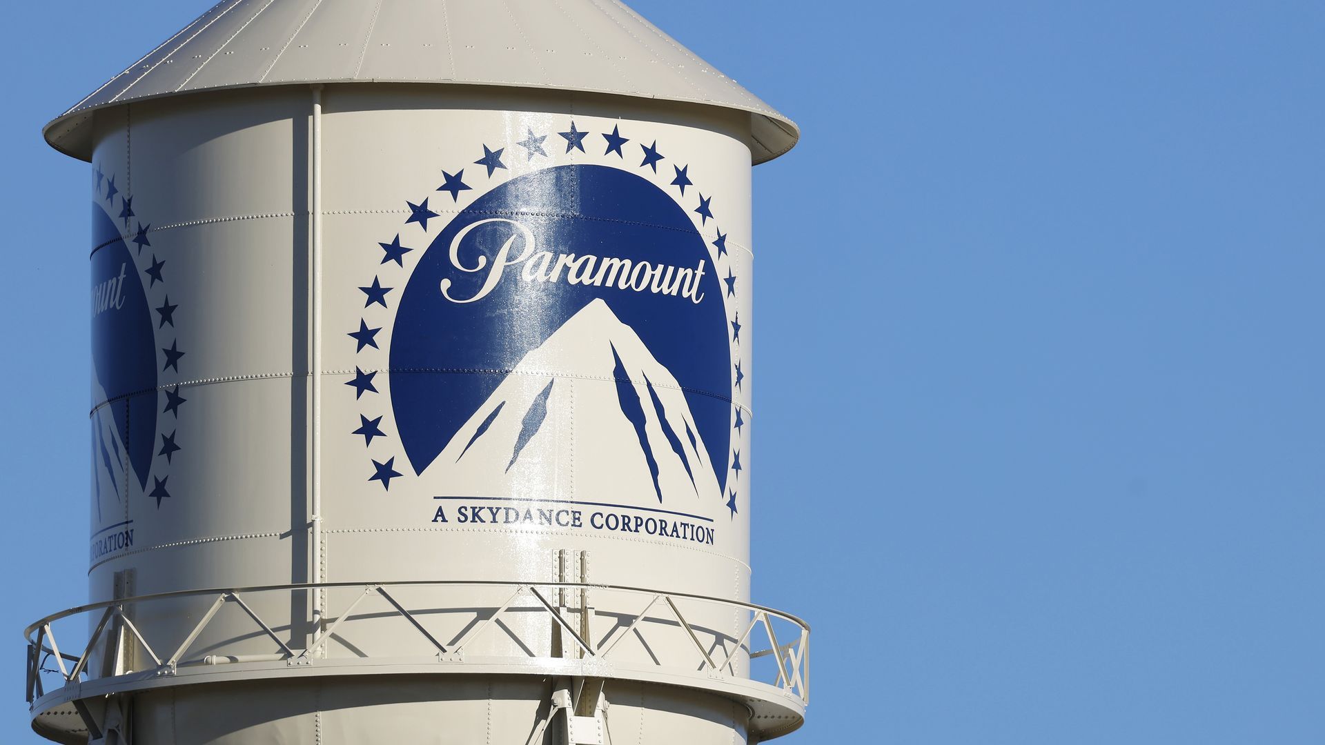 Cream-colored water tower with blue Paramount logo featuring a mountain and stars, labeled "A Skydance Corporation" against a clear blue sky.