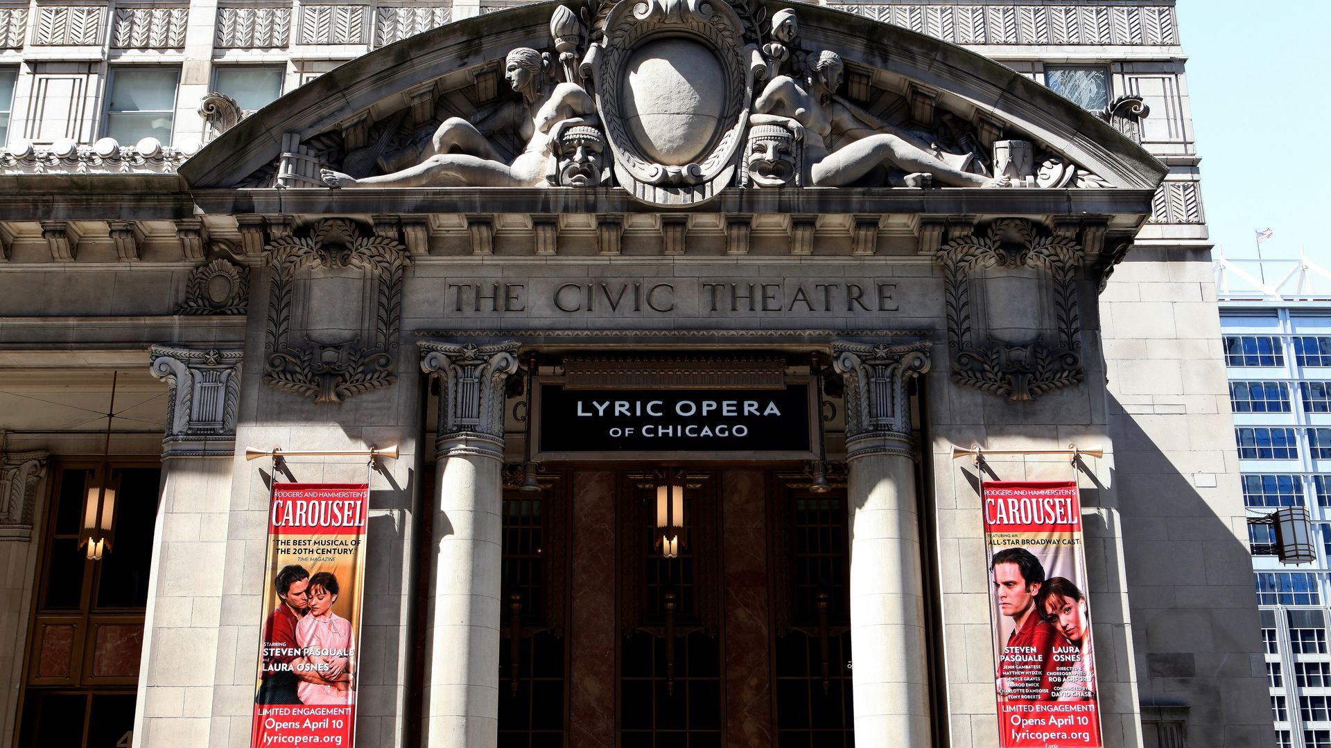 Ornate stone theater entrance with sculpted figures under a pediment reading "THE CIVIC THEATRE". Banners advertise "Lyric Opera of Chicago" and posters for "Carousel" beside the doors.