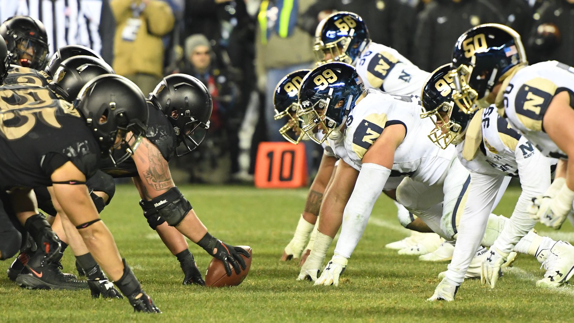 Football players lined up before the ball is snapped. 